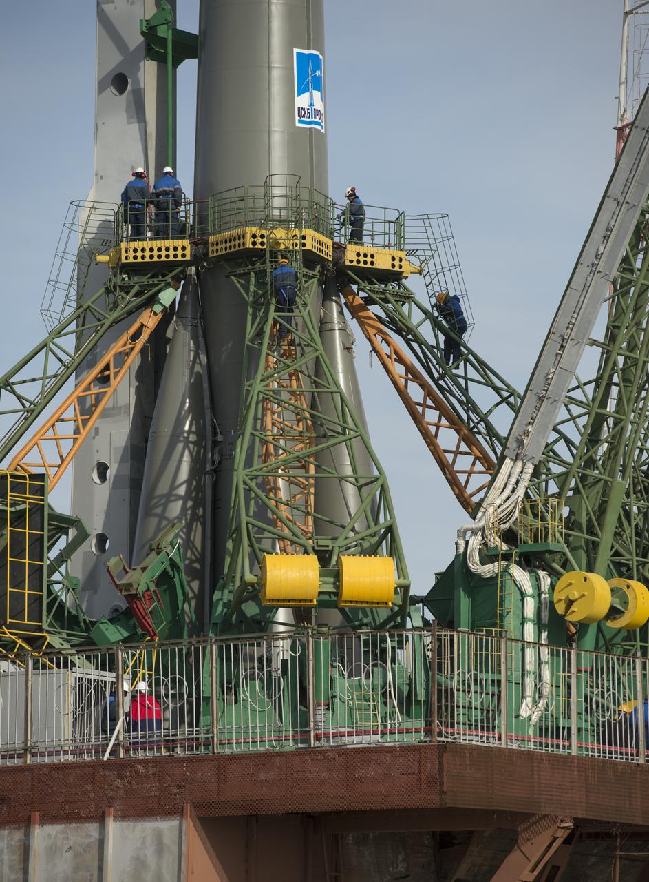 Launch pad engineers at the Baikonur Cosmodrome in Kazakhstan are dwarfed by the large gantry mechanisms at the base of the Soyuz TMA-08M rocket following its rollout to the pad on Tuesday, March 26, 2013. The rocket is being prepared for launch on March 29 to carry the crew of Expedition 35 to the International Space Station. Photo Credit: (NASA/Carla Cioffi)