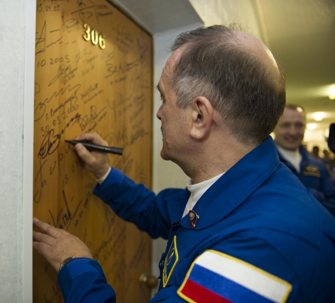 Expedition 35 Soyuz Commander Pavel Vinogradov performs the traditional door signing before he and fellow crewmates, Flight Engineers Chris Cassidy and Alexander Misurkin depart the Cosmonaut Hotel for their Soyuz launch to the International Space Station, Thursday, March 28, 2013, in Baikonur, Kazakhstan.  Launch of the Soyuz rocket will send Vinogradov, Cassidy and Misurkin on a five and a half month mission aboard the International Space Station.  Photo Credit: (NASA/Carla Cioffi)