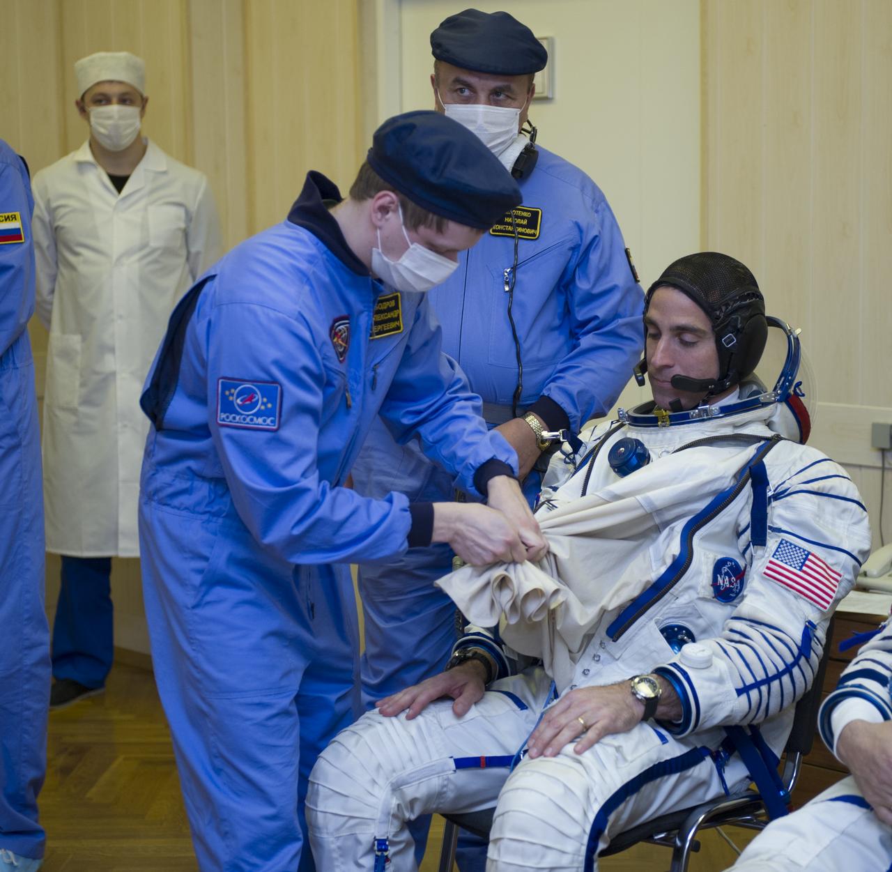 Expedition 35 NASA Flight Engineer Chris Cassidy is helped into his Russian Sokol suit as he and fellow crewmates, Soyuz Commander Pavel Vinogradov, and Flight Engineer Alexander Misurkin prepare for their Soyuz launch to the International Space Station, Thursday, March 28, 2013, in Baikonur, Kazakhstan. Launch of the Soyuz rocket will send Cassidy, Vinogradov and Misurkin on a five and a half month mission aboard the International Space Station.  Photo Credit: (NASA/GCTC/ Irina Peshkova)
