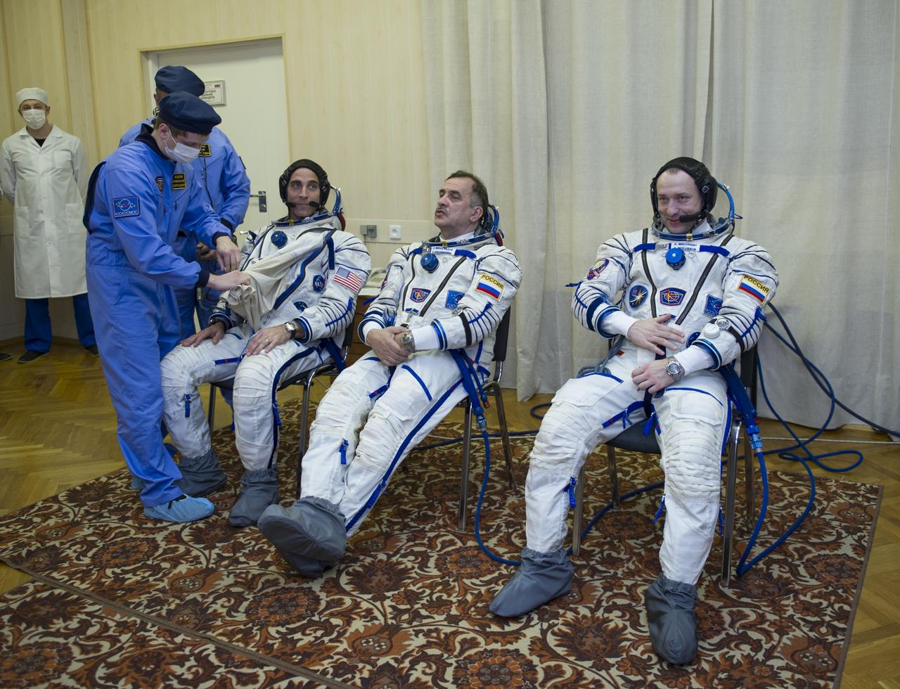 Expedition 35 NASA Flight Engineer Chris Cassidy, third from right, is helped into his Russian Sokol suit as he and fellow crewmates, Soyuz Commander Pavel Vinogradov, and Flight Engineer Alexander Misurkin prepare for their Soyuz launch to the International Space Station, Thursday, March 28, 2013, in Baikonur, Kazakhstan. Launch of the Soyuz rocket will send Cassidy, Vinogradov and Misurkin on a five and a half month mission aboard the International Space Station. Photo Credit: (NASA/GCTC/ Irina Peshkova)