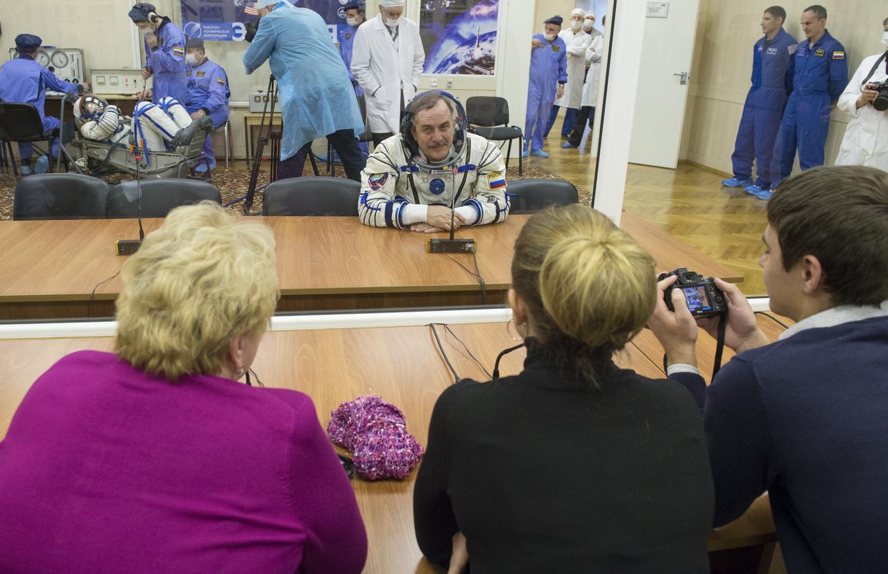 Expedition 35 Soyuz Commander Pavel Vinogradov is seen talking to family members after donning his Russian Sokol suit in preparation for his launch aboard the Soyuz rocket, Thursday, March 28, 2013, at the Baikonur Cosmodrome in Kazakhstan. Launch of the Soyuz rocket will send Vinogradov, Flight Engineer Chris Cassidy and Russian Flight Engineer Alexander Misurkin on a five and a half-month mission aboard the International Space Station. Photo Credit: (NASA/Carla Cioffi)