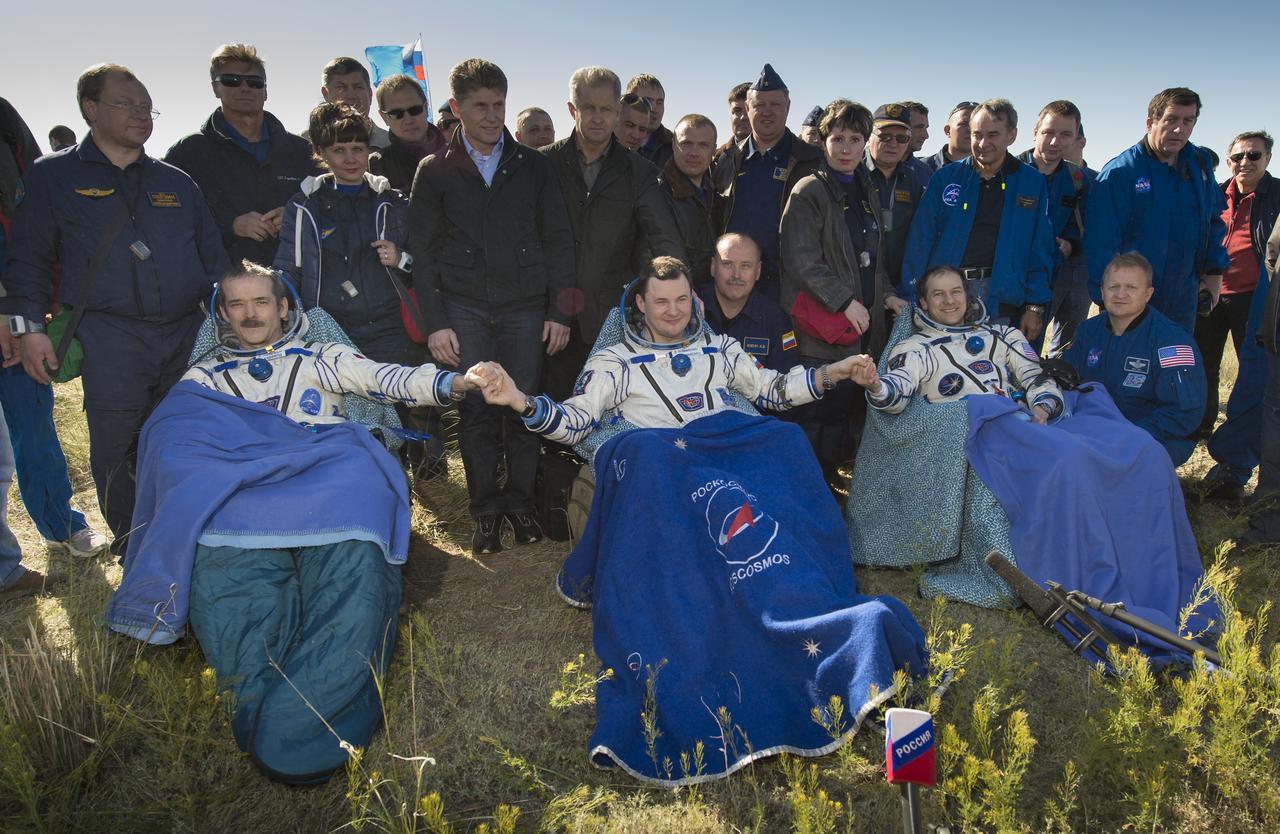 Expedition 35 Commander Chris Hadfield of the Canadian Space Agency (CSA), left, Russian Flight Engineer Roman Romanenko of the Russian Federal Space Agency (Roscosmos), center, and NASA Flight Engineer Tom Marshburn sit in chairs outside the Soyuz Capsule just minutes after they landed in a remote area outside the town of Zhezkazgan, Kazakhstan, on Tuesday, May 14, 2013. Hadfield, Romanenko and Marshburn are returning from five months onboard the International Space Station where they served as members of the Expedition 34 and 35 crews. Photo Credit: (NASA/Carla Cioffi)