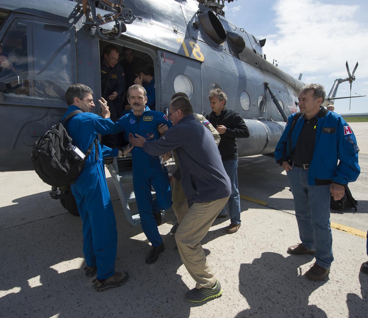 Expedition 35 Commander Chris Hadfield of the Canadian Space Agency (CSA) is helped off a Russian Search and Rescue helicopter at Karaganda Airport in Kazakhstan following his landing in the Soyuz TMA-07M spacecraft in a remote area near the town of Zhezkazgan, Kazakhstan, Tuesday, May 14, 2013.  Hadfield,  Expedition 35 NASA Flight Engineer Tom Marshburn and Russian Flight Engineer Roman Romanenko of the Russian Federal Space Agency (Roscosmos) returned to earth from more than five months onboard the International Space Station where they served as members of the Expedition 34 and 35 crews.  Photo Credit: (NASA/Carla Cioffi)