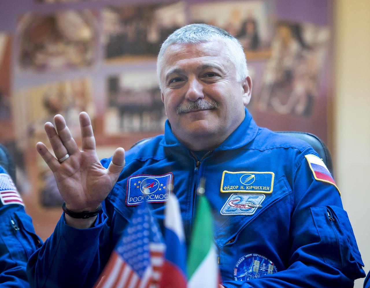 Expedition 36/37 Soyuz Commander Fyodor Yurchikhin of the Russian Federal Space Agency (Roscosmos), waves during the crew press conference at the Cosmonaut Hotel, Monday, May 27, 2013, in Kazakhstan. Yurchikin and his fellow crew members, Flight Engineers: Karen Nyberg of NASA, and Luca Parmitano of the European Space Agency, were in quarantine and kept behind glass during the press conference in preparation for their launch on a Soyuz rocket to the International Space Station (ISS) on Wednesday May 29, Kazakh time. Photo credit: (NASA/Bill Ingalls)