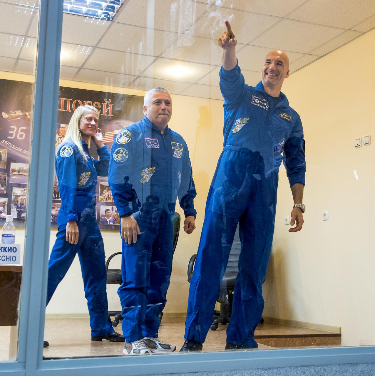 Expedition 36/37 Flight Engineer Karen Nyberg of NASA, left, Soyuz Commander Fyodor Yurchikhin of the Russian Federal Space Agency (Roscosmos), center, and Flight Engineer Luca Parmitano of the European Space Agency, are seen as they depart the crew press conference at the Cosmonaut Hotel, Monday, May 27, 2013, in Kazakhstan. The crew is in quarantine and behind glass during the press conference in preparation for their launch on a Soyuz rocket to the International Space Station (ISS) on Wednesday May 29, Kazakh time. Yurchikhin, Nyberg, and, Parmitano, will remain aboard the station until mid-November. Photo credit: (NASA/Bill Ingalls)