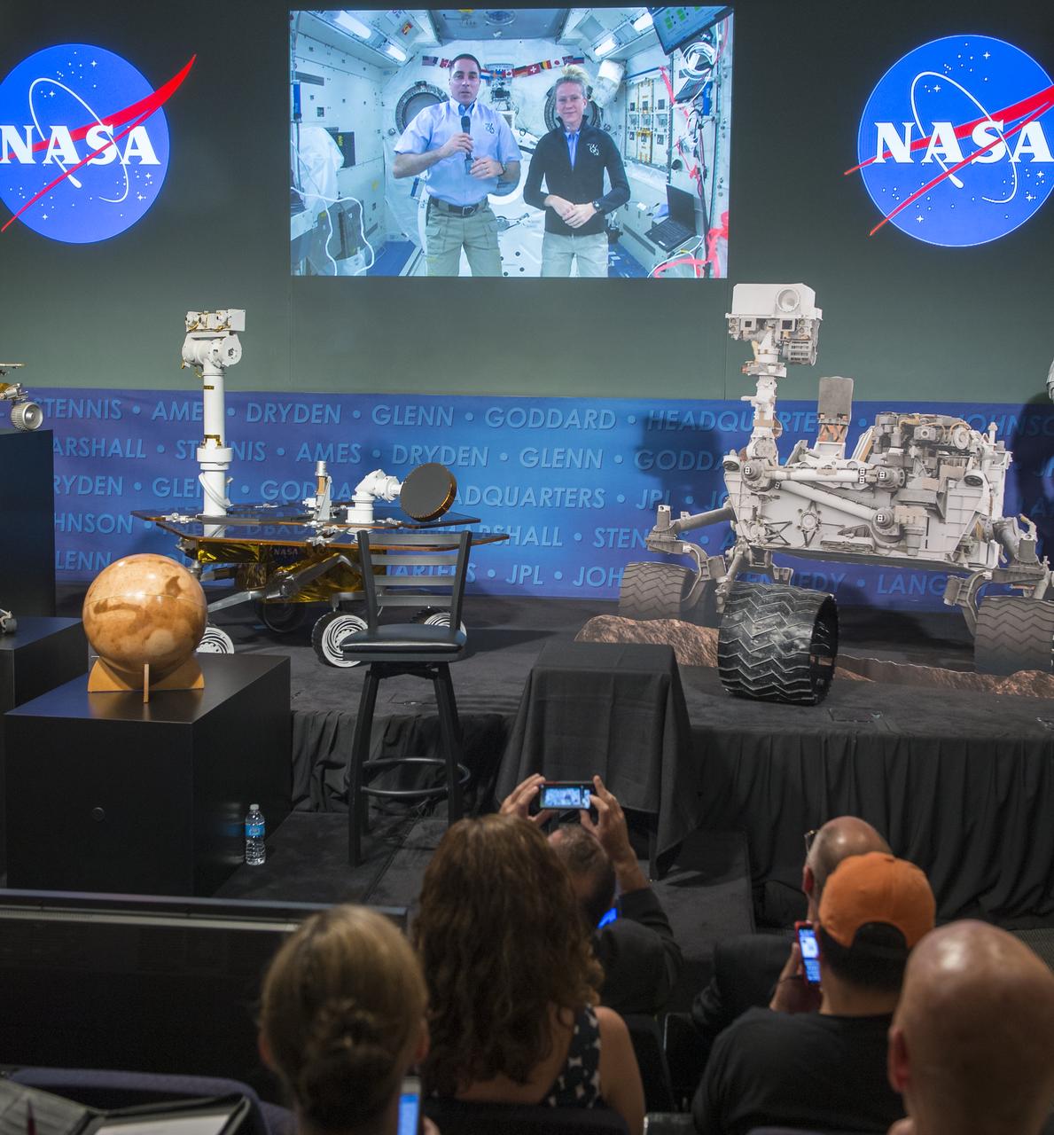 Expedition 35/36 NASA astronaut Chris Cassidy, left on screen, is seen on a live feed from the International Space Station as they participate in a public event at NASA Headquarters observing the first anniversary of the Curiosity rover's landing on Mars, Tuesday, August 6th, 2013 in Washington.  Photo Credit:  (NASA/Carla Cioffi)