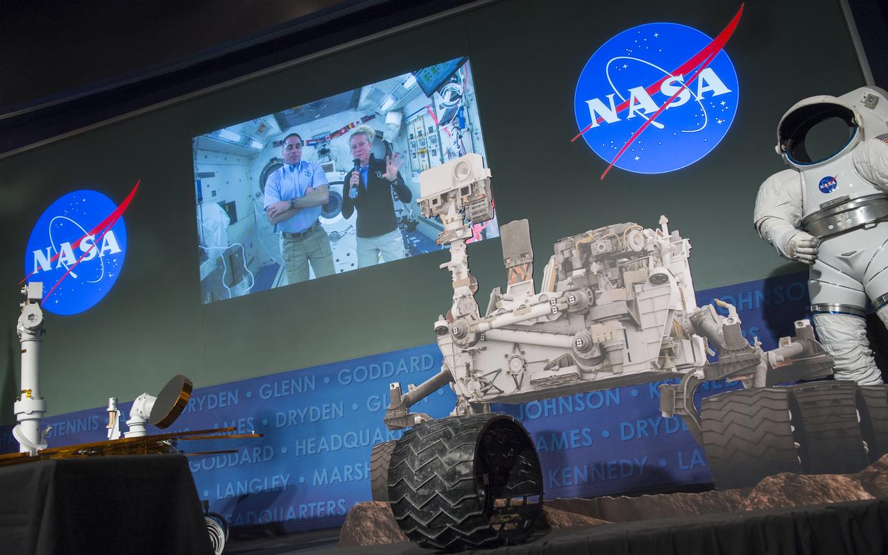 Expedition 35/36 NASA astronaut Karen Nyberg, right on screen, is seen on a live feed from the International Space Station as they participate in a public event at NASA Headquarters observing the first anniversary of the Curiosity rover's landing on Mars, Tuesday, August 6th, 2013 in Washington.  Photo Credit:  (NASA/Carla Cioffi)