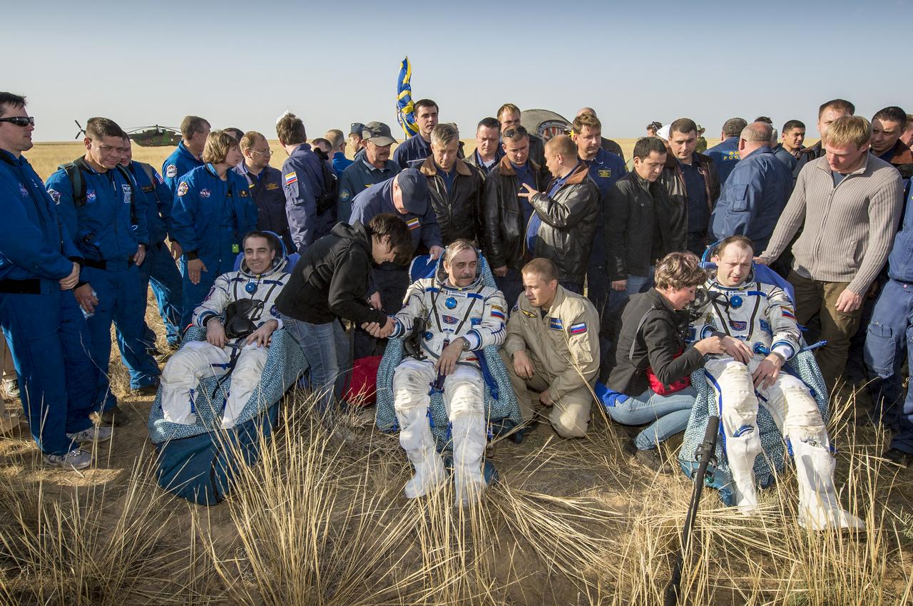 Expedition 36 Flight Engineer Chris Cassidy of NASA, left, Commander Pavel Vinogradov of the Russian Federal Space Agency (Roscosmos), center, and, Flight Engineer Alexander Misurkin of Roscosmos, sit in chairs outside the Soyuz TMA-08M capsule just minutes after they landed in a remote area near the town of Zhezkazgan, Kazakhstan, on Wednesday, Sept. 11, 2013. Vinogradov, Misurkin and Cassidy returned to Earth after five and a half months on the International Space Station. Photo Credit: (NASA/Bill Ingalls)