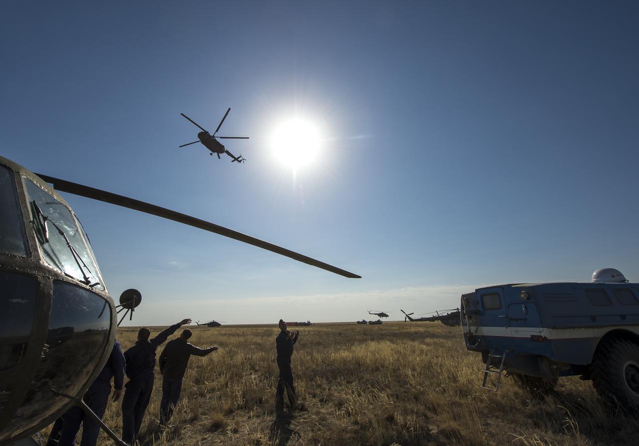 Russian search and rescue crews wave farewell to a departing helicopter as an all-terrain vehicle (ATV) with Expedition 36 Flight Engineer Chris Cassidy of NASA drops Cassidy off to from the Soyuz TMA-08M landing zone in a remote area near the town of Zhezkazgan, Kazakhstan to Karaganda on Wednesday, Sept. 11, 2013. Cassidy, Commander Pavel Vinogradov of Russian Federal Space Agency (Roscosmos), and Flight Engineer Alexander Misurkin of Roscosmos returned to Earth in a Soyuz TMA-08M capsule after five and a half months on the International Space Station. Photo Credit: (NASA/Bill Ingalls)
