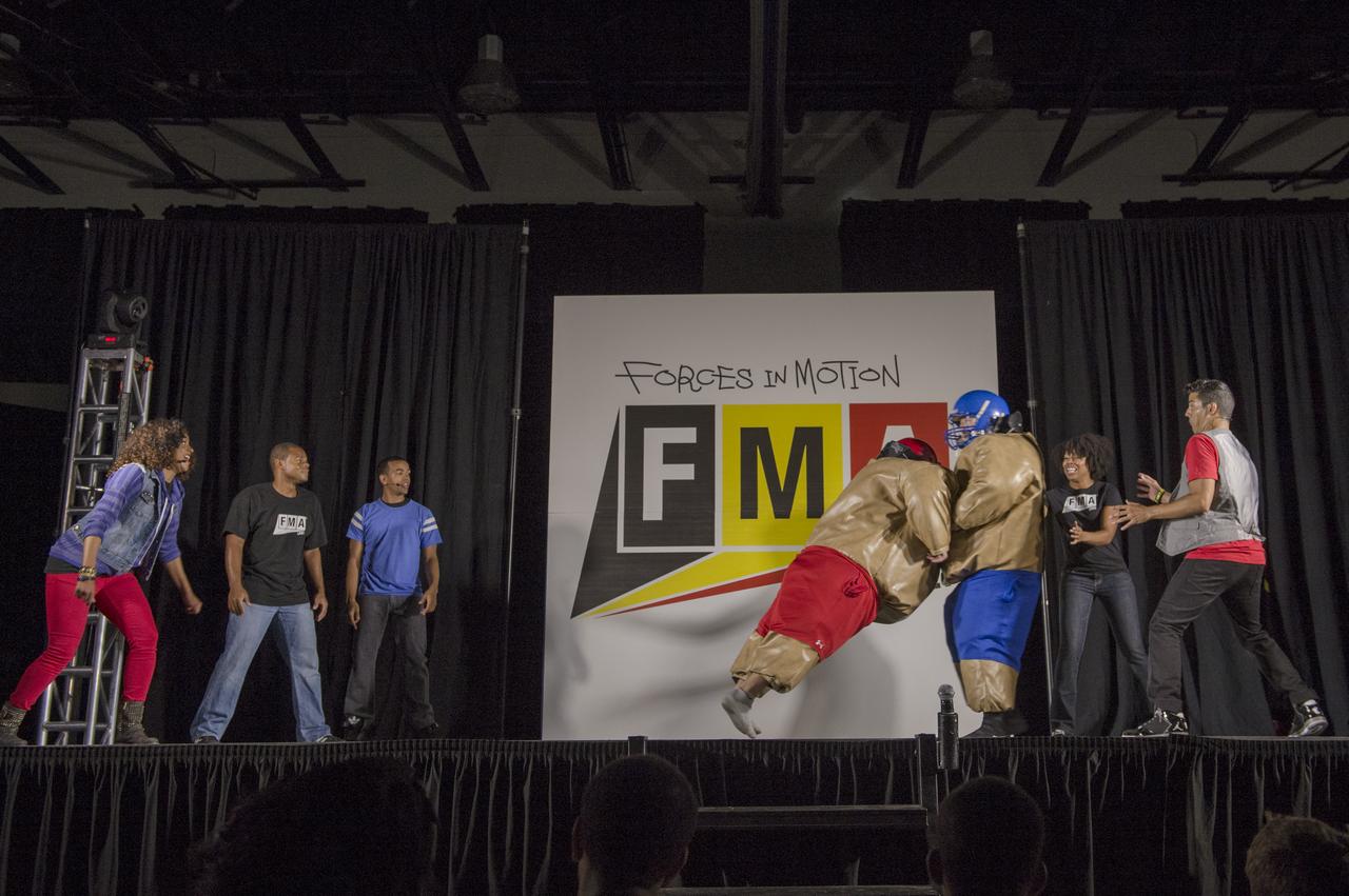 Two teachers at Hardy Middle School square off in foam suits as "FMA Live!" crew members explain Newton's third law of motion during a performance of "FMA Live!" at Hardy Middle School in Washington on Monday, Sept. 16th, 2013. "FMA Live!" is a program sponsored by NASA and Honeywell that teaches Newton's three laws of motion mixed with dance and music. The program travels across the country and has reached nearly 300,000 students.Photo Credit: (NASA/Jay Westcott)