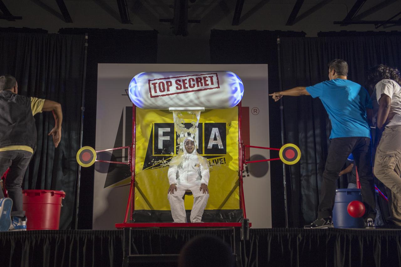 A teacher gets dunked with apple sauce during a performance of "FMA Live!" at Hardy Middle School in Washington on Monday, Sept. 16th, 2013. "FMA Live!" is a program sponsored by NASA and Honeywell that teaches Newton's three laws of motion mixed with dance and music. The program travels across the country and has reached nearly 300,000 students.Photo Credit: (NASA/Jay Westcott)
