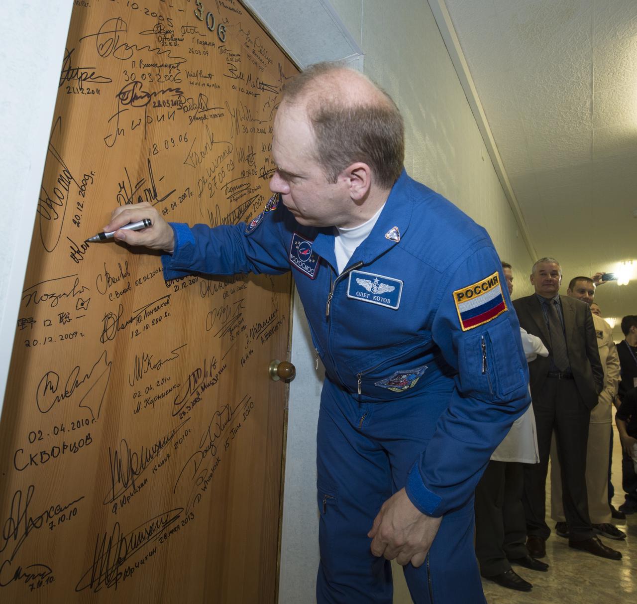 Expedition 37/38 Soyuz Commander Oleg Kotov performs the traditional door signing before he and fellow crewmates, NASA Flight Engineer Michael Hopkins, Russian Flight Engineer Sergey Ryazanskiy depart the Cosmonaut Hotel for their Soyuz launch to the International Space Station on Wednesday, Sept. 25, 2013, in Baikonur, Kazakhstan. Launch of the Soyuz rocket will send Hopkins, Kotov and Ryazanskiy on a five-month mission aboard the International Space Station.  Photo Credit: (NASA/Carla Cioffi)