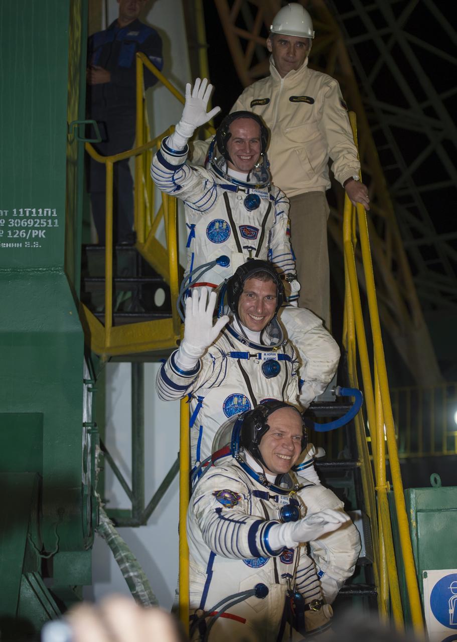 Expedition 37 Russian Flight Engineer Sergey Ryazanskiy, top, NASA Flight Engineer Michael Hopkins, Soyuz Commander Oleg Kotov, bottom, wave farewell from the base of the Soyuz rocket at the Baikonur Cosmodrome in Baikonur, Kazakhstan, Thursday, Sept. 26, 2013.  Their Soyuz TMA-10M rocket launched at 2:58 a.m. local time.  Photo Credit: (NASA/Carla Cioffi)