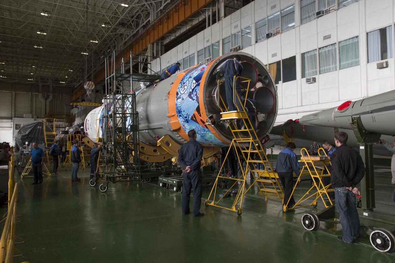 Workers make final preperations to a Soyuz TMA-11M spacecraft on Monday, Nov. 4, 2013, at the Baikonur Cosmodome in Baikonur, Kazakhstan. The rocket is adorned with the logo of the Sochi Olympic Organizing Committee and other related artwork to commemorate the launch of the Olympic torch with the crew for a four-day visit to the station. The torch will return to Earth with another trio of station residents on Nov. 11 and will be part of the torch relay that ends with the lighting of the flame at the Fisht Stadium in Sochi, Russia Feb. 7 to mark the opening of the 2014 Winter Olympics. Photo Credit: (NASA/Victor Zelentsov)