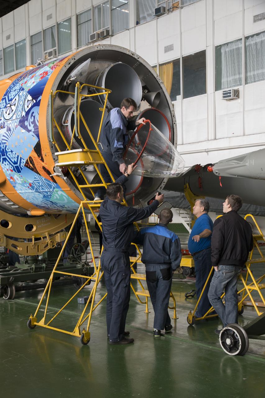 Workers make final preperations to a Soyuz TMA-11M spacecraft on Monday, Nov. 4, 2013, at the Baikonur Cosmodome in Baikonur, Kazakhstan. The rocket is adorned with the logo of the Sochi Olympic Organizing Committee and other related artwork to commemorate the launch of the Olympic torch with the crew for a four-day visit to the station. The torch will return to Earth with another trio of station residents on Nov. 11 and will be part of the torch relay that ends with the lighting of the flame at the Fisht Stadium in Sochi, Russia Feb. 7 to mark the opening of the 2014 Winter Olympics. Photo Credit: (NASA/Victor Zelentsov)