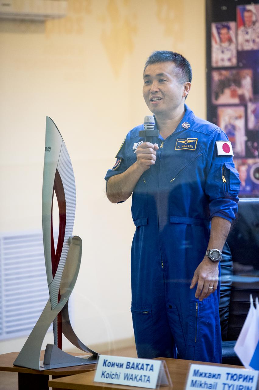 Expedition 38 Flight Engineer Koichi Wakata of the Japan Aerospace Exploration Agency is seen in quarantine, behind glass, during the final press conference held a day ahead of his launch with fellow crew mates, Expedition 38 Soyuz Commander Mikhail Tyurin of Roscosmos, and, Flight Engineer Rick Mastracchio of NASA, to the International Space Station, Wednesday, Nov. 6, 2013 at the Cosmonaut Hotel in Baikonur, Kazakhstan.  An Olympic torch that will be launched with the crew for a four-day visit to the station is seen on the left. The torch will return to Earth with another trio of station residents on Nov. 11 and will be part of the torch relay that ends with the lighting of the flame at the Fisht Stadium in Sochi, Russia Feb. 7 to mark the opening of the 2014 Winter Olympics.  Photo Credit: (NASA/Bill Ingalls)