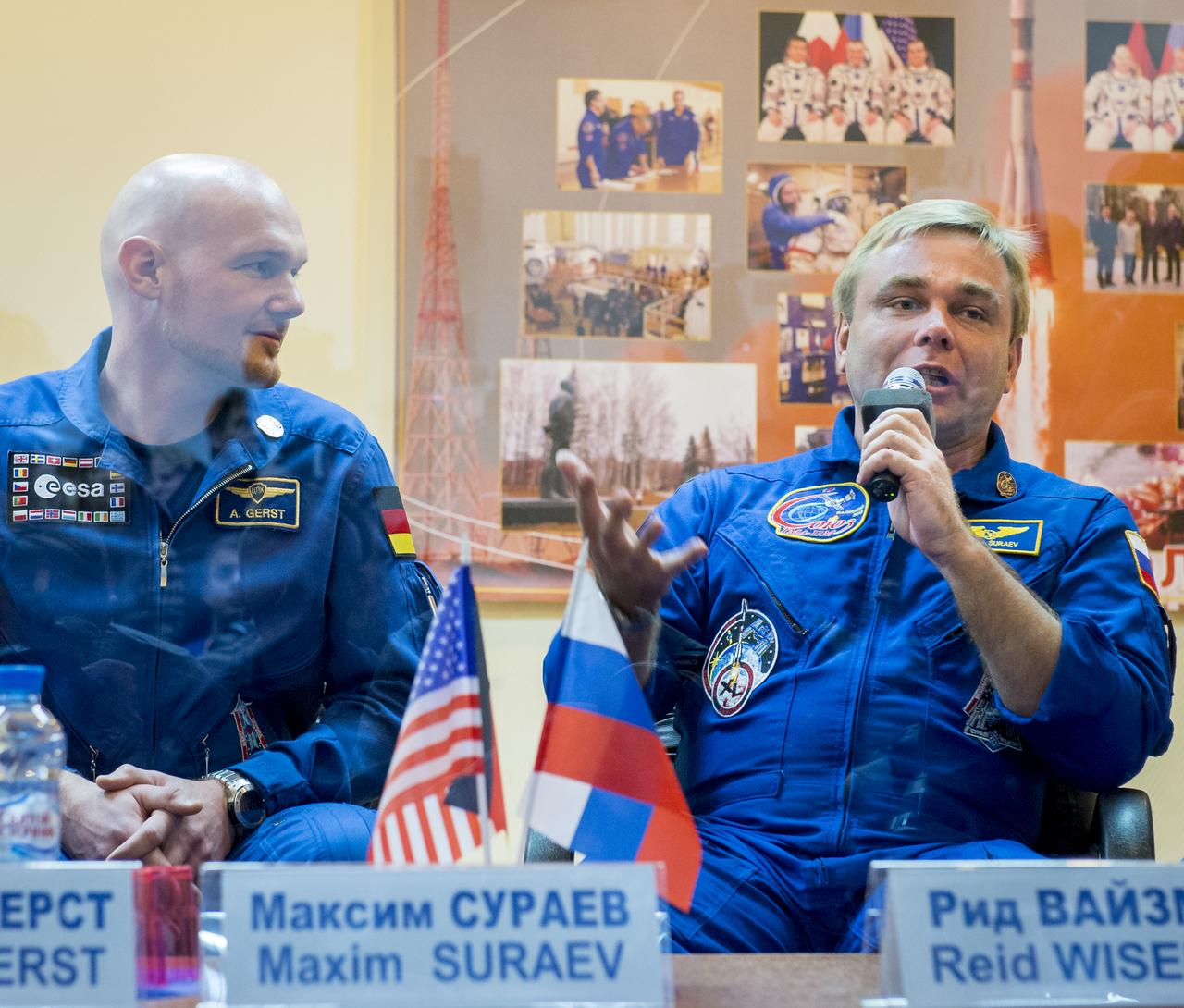 Expedition 38 backup crew members Alexander Gerst of the European Space Agency, left, and, Russian cosmonaut Max Suraev, are seen in quarantine, behind glass, during the final press conference held a day ahead of the launch of Expedition 38 prime crew members; Flight Engineer Koichi Wakata of the Japan Aerospace Exploration Agency, Soyuz Commander Mikhail Tyurin of Roscosmos, and, Flight Engineer Rick Mastracchio of NASA, to the International Space Station, Wednesday, Nov. 6, 2013 at the Cosmonaut Hotel in Baikonur, Kazakhstan.  Photo Credit: (NASA/Bill Ingalls)