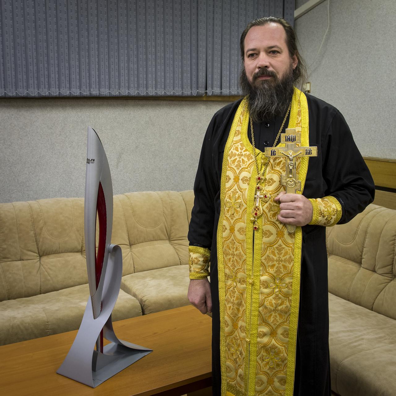 Portrait of Orthodox priest, Father Sergei with the 2014 Sochi Olympic torch that is to be launched with Expedition 38 Soyuz Commander Mikhail Tyurin of Roscosmos, Flight Engineer Koichi Wakata of the Japan Aerospace Exploration Agency, and, Flight Engineer Rick Mastracchio of NASA, Cosmonaut hotel, Thursday, Nov. 7, 2013, in Baikonur, Kazakhstan. Father Sergei was waiting to provide the traditional blessing for the crew prior to their departure from the hotel.  The Olympic torch will have a four-day visit to the International Space Station and will return to Earth with another trio of station residents on Nov. 11 and will be part of the torch relay that ends with the lighting of the flame at the Fisht Stadium in Sochi, Russia Feb. 7 to mark the opening of the 2014 Winter Olympics. Photo Credit (NASA/Bill Ingalls)