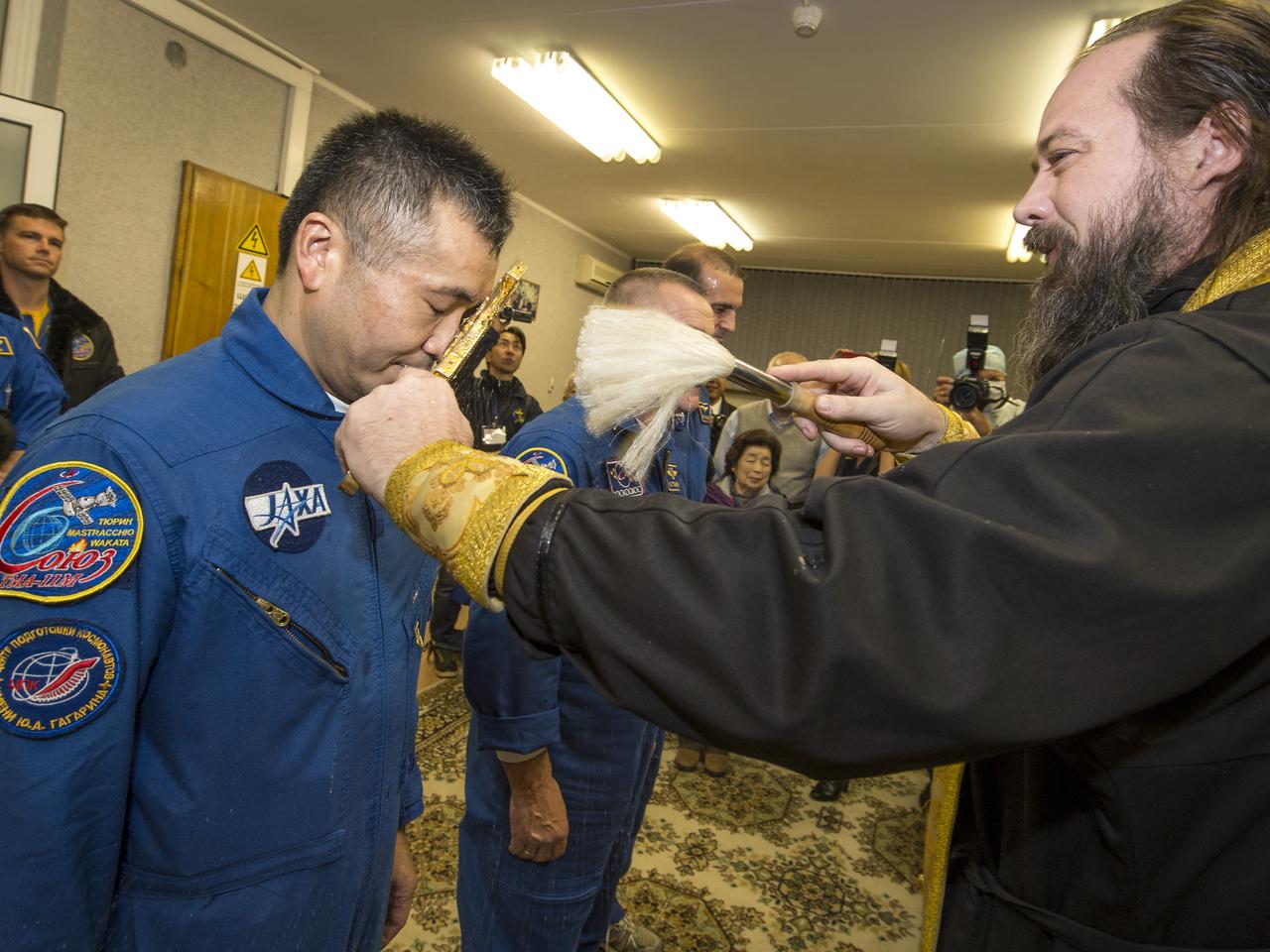 Expedition 38 Flight Engineer Koichi Wakata of the Japan Aerospace Exploration Agency receives the traditional blessing from a Russian Orthodox priest at the Cosmonaut Hotel prior to his launch on the Soyuz rocket to the International Space Station with Flight Engineer Rick Mastracchio of NASA, and, Soyuz Commander Mikhail Tyurin of Roscosmos, Thursday, Nov. 7, 2013, in Baikonur, Kazakhstan. Tyurin, Wakata, and, Mastracchio will launch in their Soyuz TMA-11M spacecraft to the International Space Station to begin a six-month mission. Photo Credit (NASA/Bill Ingalls)
