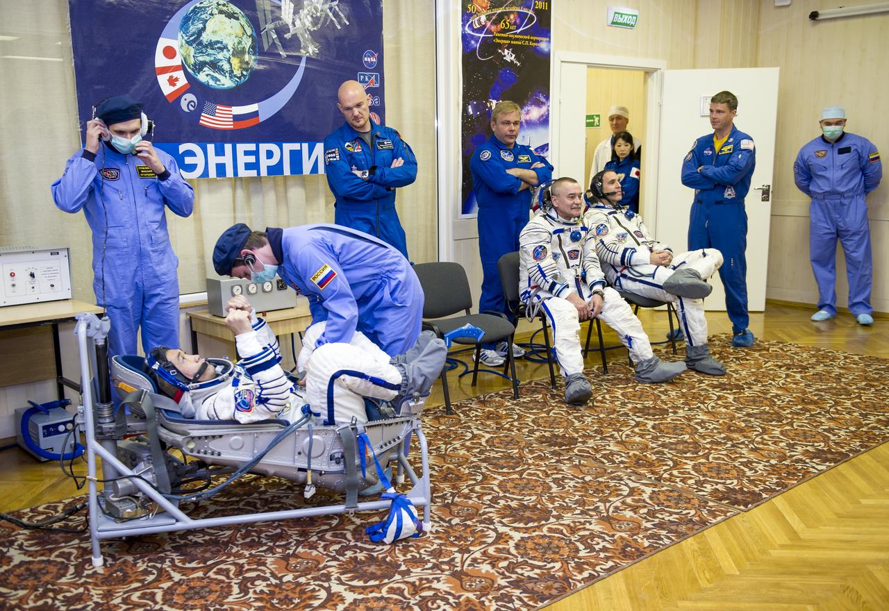 Expedition 38 Flight Engineer Koichi Wakata of the Japan Aerospace Exploration Agency is seen laying in a seat liner as he and fellow crew mates, Soyuz Commander Mikhail Tyurin of Roscosmos, seated left, and, Flight Engineer Rick Mastracchio of NASA, have their Russian Sokol suits pressure checked a few hours ahead of their launch, Thursday, Nov. 7, 2013, in Baikonur, Kazakhstan. Tyurin, Wakata, and, Mastracchio will launch in their Soyuz TMA-11M spacecraft to the International Space Station to begin a six-month mission. Photo Credit: (NASA/GCTC/Irina Peshkova)