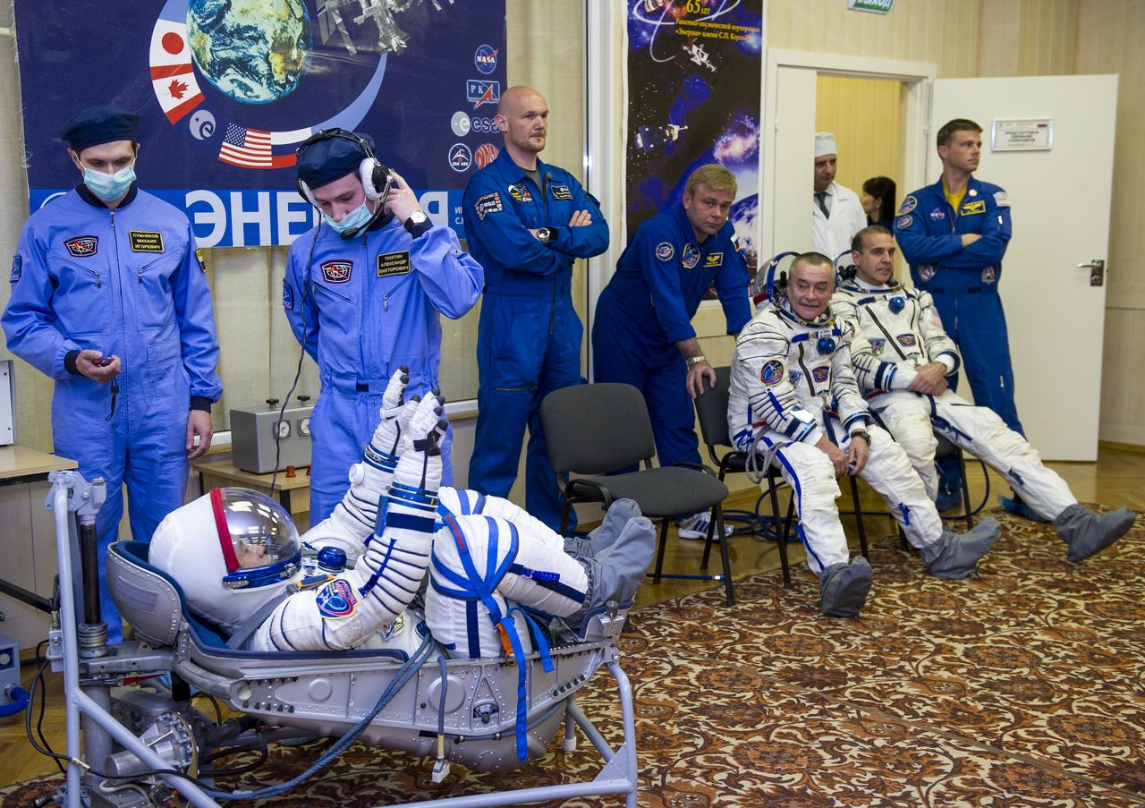 Expedition 38 Flight Engineer Koichi Wakata of the Japan Aerospace Exploration Agency is seen laying in a seat liner as he and fellow crew mates, Soyuz Commander Mikhail Tyurin of Roscosmos, seated left, and, Flight Engineer Rick Mastracchio of NASA, have their Russian Sokol suits pressure checked a few hours ahead of their launch, Thursday, Nov. 7, 2013, in Baikonur, Kazakhstan. Tyurin, Wakata, and, Mastracchio will launch in their Soyuz TMA-11M spacecraft to the International Space Station to begin a six-month mission. Photo Credit: (NASA/GCTC/Irina Peshkova)