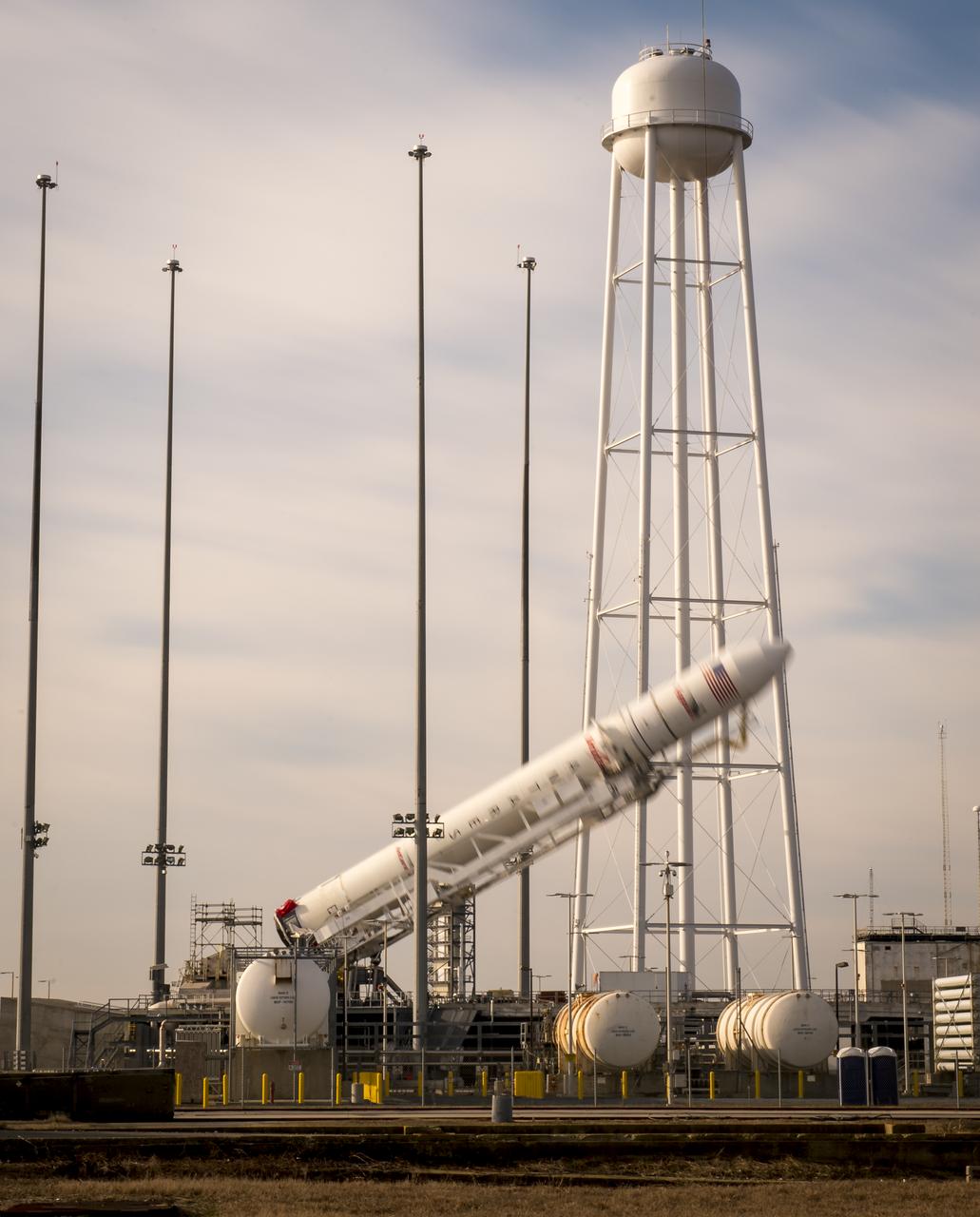 The Orbital Science Corporation Antares rocket is seen in this 30 second exposure as it is raised into position at launch Pad-0A, Tuesday, December 17, 2013, at NASA's Wallops Flight Facility, Wallops Island, VA. The Antares will launch a Cygnus spacecraft on a cargo resupply mission to the International Space Station. The Orbital-1 mission is Orbital Sciences' first contracted cargo delivery flight to the space station for NASA. Among the cargo aboard Cygnus set to launch to the space station are science experiments, crew provisions, spare parts and other hardware. Launch is scheduled for 9:19 p.m. EST on Thursday, Dec. 19. Weather permitting, it may be widely visible along the east coast of the United States. Photo Credit: (NASA/Bill Ingalls)