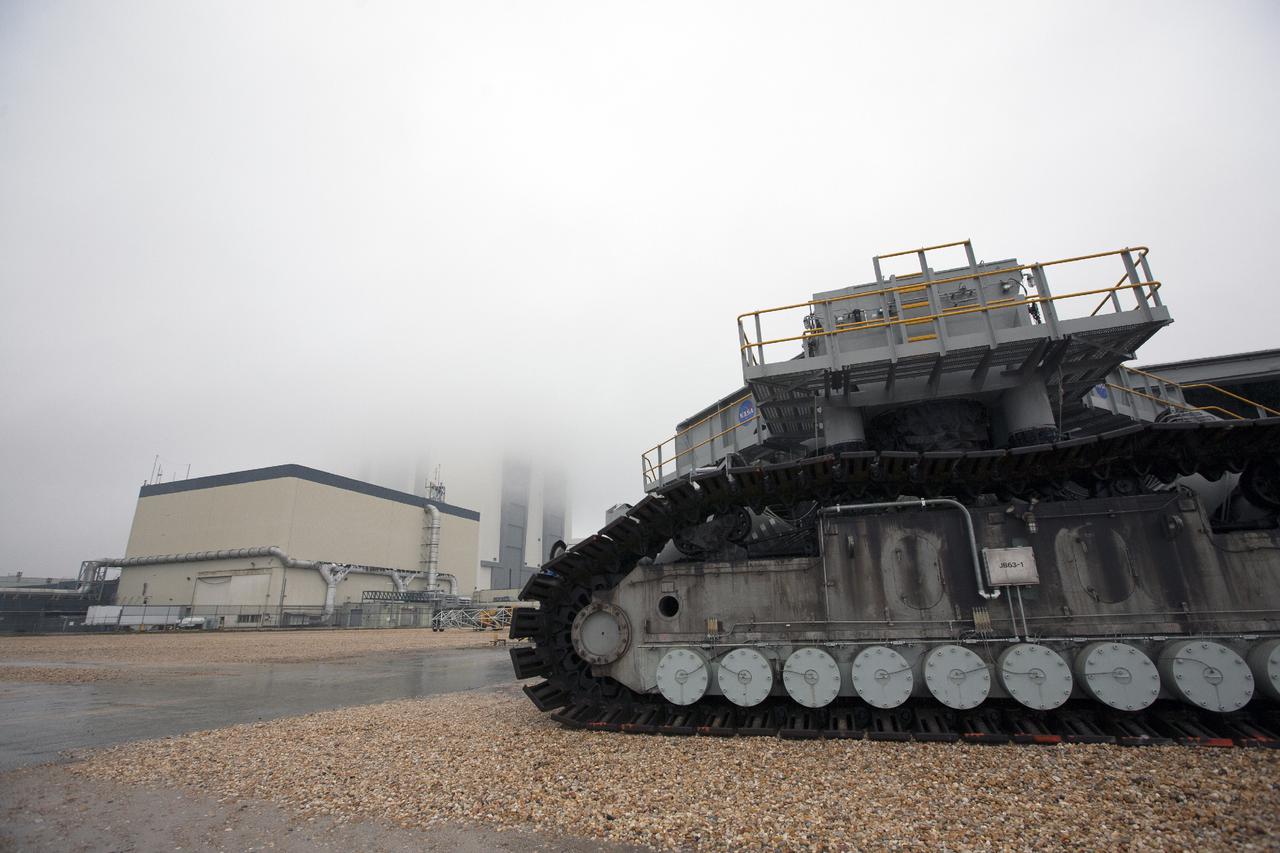 CAPE CANAVERAL, Fla. – Crawler-transporter 2, or CT-2, travels along the crawlerway toward the Vehicle Assembly Building, or VAB, at NASA’s Kennedy Space Center in Florida. The VAB is partially hidden by fog. The Ground Systems Development and Operations Program completed a roller bearing assembly test on CT-2 truck sections A and C. The left- and right-hand steering was tested in both directions. The temperature of the roller assemblies was monitored and recorded. Engineers and technicians performed visual inspections of the roller bearing pumps, valves and lines to ensure that the grease injectors worked properly and provided the required flow of grease to the new roller assemblies.  Work continues in high bay 2 to upgrade CT-2. The modifications are designed to ensure CT-2’s ability to transport launch vehicles currently in development, such as the agency’s Space Launch System, to the launch pad. The Ground Systems Development and Operations Program office at Kennedy is overseeing the upgrades. For more than 45 years the crawler-transporters were used to transport the mobile launcher platform and the Apollo-Saturn V rockets and, later, space shuttles to Launch Pads 39A and B. For more information, visit: http:__www.nasa.gov_exploration_systems_ground_crawler-transporter. Photo credit: NASA_Kim Shiflett