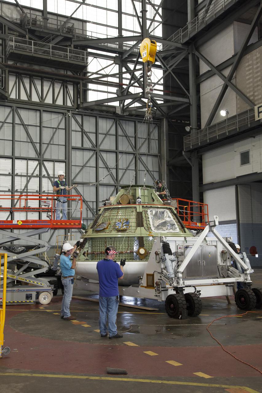 CAPE CANAVERAL, Fla. – Inside the Vehicle Assembly Building at NASA’s Kennedy Space Center in Florida, technicians on scissor lifts secure the lines of a bridge crane attached to the Orion ground test vehicle for heat shield removal. The ground test vehicle is being prepared for its move to Langley Research Center in Hampton, Va., for a water test. The test vehicle is being used by the Ground Systems Development and Operations Program for path finding operations, including simulated manufacturing, assembly and stacking procedures. Orion is the exploration spacecraft designed to carry astronauts to destinations not yet explored by humans. It will have emergency abort capability, sustain the crew during space travel and provide safe re-entry from deep space return velocities. The first unpiloted test flight of Orion is scheduled to launch in 2014 atop a Delta IV Heavy rocket and in 2017 on NASA’s Space Launch System rocket. For more information, visit www.nasa.gov_orion. Photo credit: Daniel Casper
