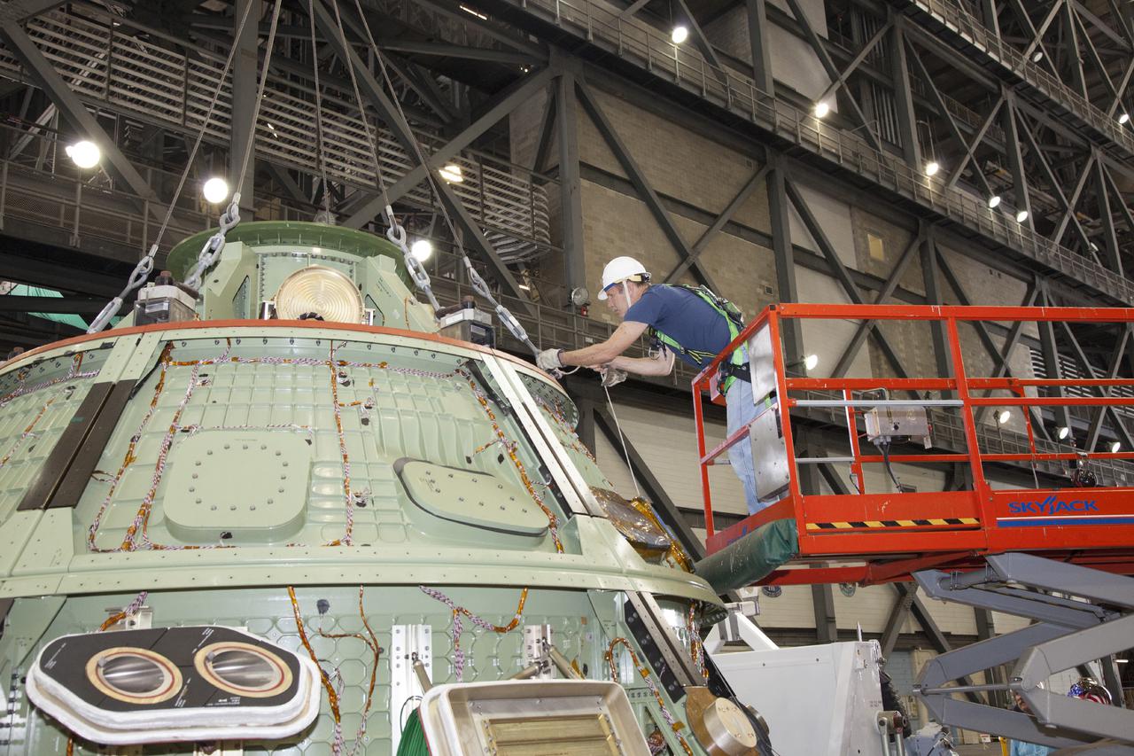 CAPE CANAVERAL, Fla. – Inside the Vehicle Assembly Building at NASA’s Kennedy Space Center in Florida, a technician on scissor lift secures the lines of a bridge crane attached to the Orion ground test vehicle for heat shield removal. The ground test vehicle is being prepared for its move to Langley Research Center in Hampton, Va., for a water test. The test vehicle is being used by the Ground Systems Development and Operations Program for path finding operations, including simulated manufacturing, assembly and stacking procedures. Orion is the exploration spacecraft designed to carry astronauts to destinations not yet explored by humans. It will have emergency abort capability, sustain the crew during space travel and provide safe re-entry from deep space return velocities. The first unpiloted test flight of Orion is scheduled to launch in 2014 atop a Delta IV Heavy rocket and in 2017 on NASA’s Space Launch System rocket. For more information, visit www.nasa.gov_orion. Photo credit: Daniel Casper