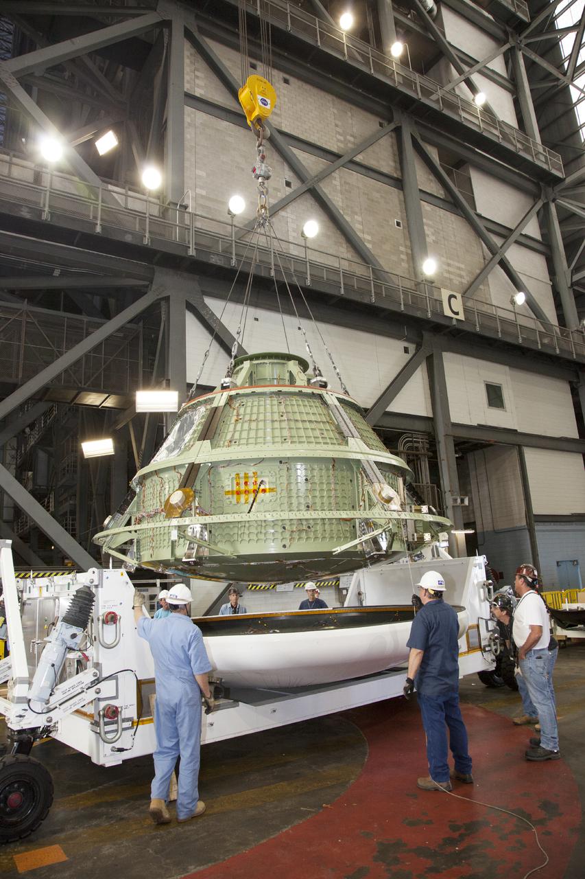 CAPE CANAVERAL, Fla. – Inside the Vehicle Assembly Building at NASA’s Kennedy Space Center in Florida, technicians monitor the progress as a bridge crane attached to the Orion ground test vehicle begins to lift it away from the heat shield. The ground test vehicle is being prepared for its move to Langley Research Center in Hampton, Va., for a water test. The test vehicle is being used by the Ground Systems Development and Operations Program for path finding operations, including simulated manufacturing, assembly and stacking procedures. Orion is the exploration spacecraft designed to carry astronauts to destinations not yet explored by humans. It will have emergency abort capability, sustain the crew during space travel and provide safe re-entry from deep space return velocities. The first unpiloted test flight of Orion is scheduled to launch in 2014 atop a Delta IV Heavy rocket and in 2017 on NASA’s Space Launch System rocket. For more information, visit www.nasa.gov_orion. Photo credit: Daniel Casper