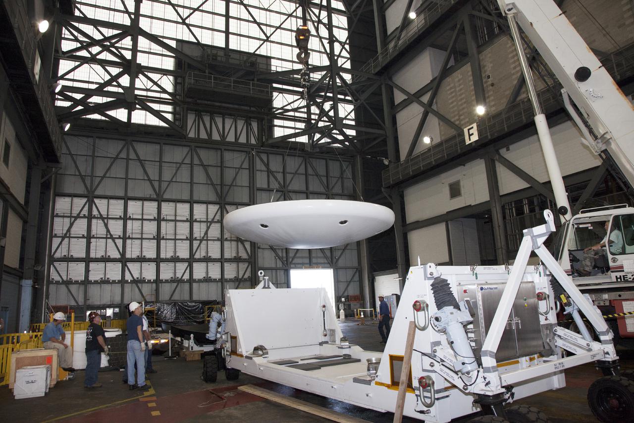 CAPE CANAVERAL, Fla. – Inside the Vehicle Assembly Building at NASA’s Kennedy Space Center in Florida, technicians monitor the progress as a crane moves the heat shield that was removed from the Orion ground test vehicle toward a special holding platform. The ground test vehicle is being prepared for its move to Langley Research Center in Hampton, Va., for a water test. The test vehicle is being used by the Ground Systems Development and Operations Program for path finding operations, including simulated manufacturing, assembly and stacking procedures. Orion is the exploration spacecraft designed to carry astronauts to destinations not yet explored by humans. It will have emergency abort capability, sustain the crew during space travel and provide safe re-entry from deep space return velocities. The first unpiloted test flight of Orion is scheduled to launch in 2014 atop a Delta IV Heavy rocket and in 2017 on NASA’s Space Launch System rocket. For more information, visit www.nasa.gov_orion. Photo credit: Daniel Casper