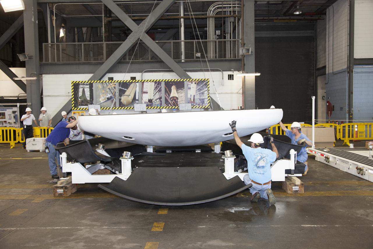 CAPE CANAVERAL, Fla. – Inside the Vehicle Assembly Building at NASA’s Kennedy Space Center in Florida, technicians assist as a crane lowers the heat shield that was removed from the Orion ground test vehicle onto a special holding platform. The ground test vehicle is being prepared for its move to Langley Research Center in Hampton, Va., for a water test. The test vehicle is being used by the Ground Systems Development and Operations Program for path finding operations, including simulated manufacturing, assembly and stacking procedures. Orion is the exploration spacecraft designed to carry astronauts to destinations not yet explored by humans. It will have emergency abort capability, sustain the crew during space travel and provide safe re-entry from deep space return velocities. The first unpiloted test flight of Orion is scheduled to launch in 2014 atop a Delta IV Heavy rocket and in 2017 on NASA’s Space Launch System rocket. For more information, visit www.nasa.gov_orion. Photo credit: Daniel Casper