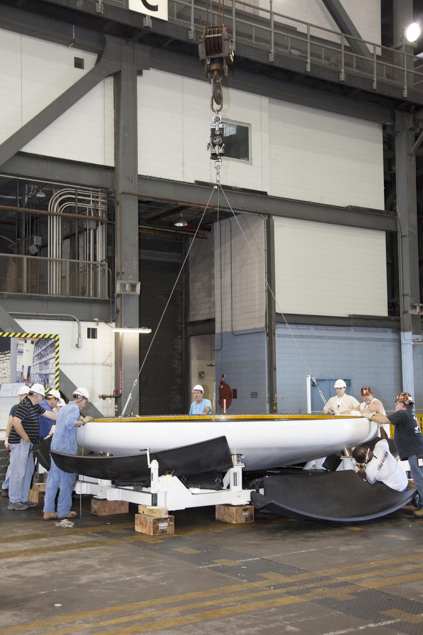 CAPE CANAVERAL, Fla. – Inside the Vehicle Assembly Building at NASA’s Kennedy Space Center in Florida, technicians help secure the heat shield that was removed from the Orion ground test vehicle onto a special holding platform. The ground test vehicle is being prepared for its move to Langley Research Center in Hampton, Va., for a water test. The test vehicle is being used by the Ground Systems Development and Operations Program for path finding operations, including simulated manufacturing, assembly and stacking procedures. Orion is the exploration spacecraft designed to carry astronauts to destinations not yet explored by humans. It will have emergency abort capability, sustain the crew during space travel and provide safe re-entry from deep space return velocities. The first unpiloted test flight of Orion is scheduled to launch in 2014 atop a Delta IV Heavy rocket and in 2017 on NASA’s Space Launch System rocket. For more information, visit www.nasa.gov_orion. Photo credit: Daniel Casper