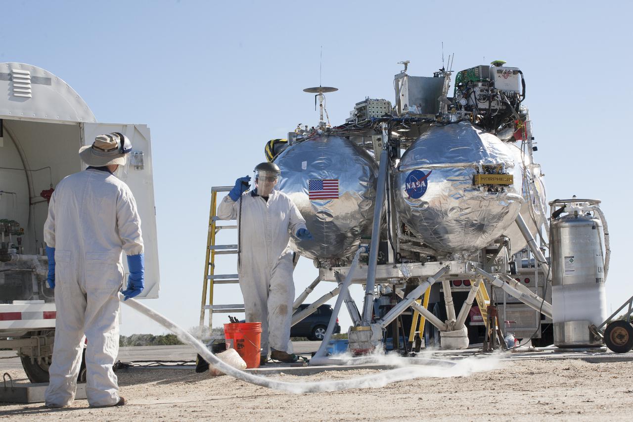 CAPE CANAVERAL, Fla. – Technicians prepare the Project Morpheus prototype lander for its fifth free flight test at the north end of the Shuttle Landing Facility at NASA’s Kennedy Space Center in Florida. The 74-second test began around 1 p.m. EST with the Morpheus lander launching from the ground over a flame trench and ascending 467 feet, more than 160 feet higher than its last test. Morpheus flew forward, covering 637 feet in 30 second before descending and landing on target on a dedicated pad inside the autonomous landing and hazard avoidance technology, or ALHAT, hazard field. Project Morpheus tests NASA’s ALHAT and an engine that runs on liquid oxygen and methane, or green propellants, into a fully-operational lander that could deliver cargo to other planetary surfaces.  The landing facility provides the lander with the kind of field necessary for realistic testing, complete with rocks, craters and hazards to avoid. Morpheus’ ALHAT payload will allow it to navigate to clear landing sites amidst rocks, craters and other hazards during its descent. Project Morpheus is being managed under the Advanced Exploration Systems, or AES, Division in NASA’s Human Exploration and Operations Mission Directorate. The efforts in AES pioneer new approaches for rapidly developing prototype systems, demonstrating key capabilities and validating operational concepts for future human missions beyond Earth orbit. For more information, visit http:__morpheuslander.jsc.nasa.gov. Photo credit: NASA_Kim Shiflett