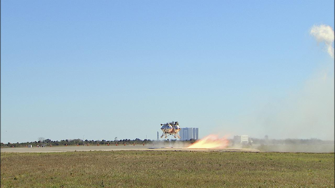 CAPE CANAVERAL, Fla. – The fifth free flight of the Project Morpheus prototype lander was conducted at the north end of the Shuttle Landing Facility at NASA’s Kennedy Space Center in Florida. The 74-second test began at about 1 p.m. EST with the Morpheus lander launching from the ground over a flame trench and ascending about to 476 feet, more than 160 feet higher than its last test. The lander flew forward, covering 637 feet in 30 seconds before descending and landing on target on a dedicated landing pad inside the autonomous landing and hazard avoidance technology, or ALHAT, hazard field. Project Morpheus tests NASA’s ALHAT and an engine that runs on liquid oxygen and methane, or green propellants, into a fully-operational lander that could deliver cargo to other planetary surfaces.  The landing facility provides the lander with the kind of field necessary for realistic testing, complete with rocks, craters and hazards to avoid. Morpheus’ ALHAT payload allows it to navigate to clear landing sites amidst rocks, craters and other hazards during its descent. Project Morpheus is being managed under the Advanced Exploration Systems, or AES, Division in NASA’s Human Exploration and Operations Mission Directorate. The efforts in AES pioneer new approaches for rapidly developing prototype systems, demonstrating key capabilities and validating operational concepts for future human missions beyond Earth orbit. For more information on Project Morpheus, visit http:__www.nasa.gov_centers_johnson_exploration_morpheus.  Photo credit: NASA_Frankie Martin