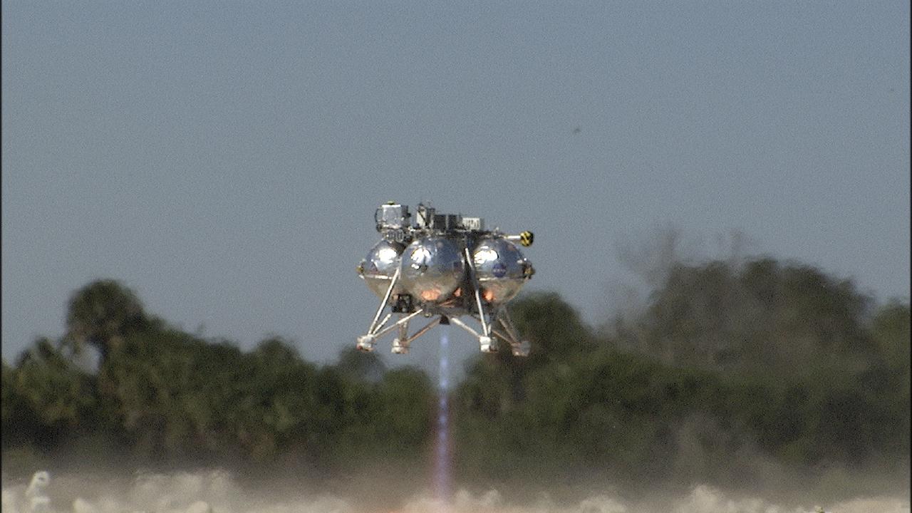 CAPE CANAVERAL, Fla. – The fifth free flight of the Project Morpheus prototype lander was conducted at the north end of the Shuttle Landing Facility at NASA’s Kennedy Space Center in Florida. The 74-second test began at about 1 p.m. EST with the Morpheus lander launching from the ground over a flame trench and ascending about to 476 feet, more than 160 feet higher than its last test. The lander flew forward, covering 637 feet in 30 seconds before descending and landing on target on a dedicated landing pad inside the autonomous landing and hazard avoidance technology, or ALHAT, hazard field. Project Morpheus tests NASA’s ALHAT and an engine that runs on liquid oxygen and methane, or green propellants, into a fully-operational lander that could deliver cargo to other planetary surfaces.  The landing facility provides the lander with the kind of field necessary for realistic testing, complete with rocks, craters and hazards to avoid. Morpheus’ ALHAT payload allows it to navigate to clear landing sites amidst rocks, craters and other hazards during its descent. Project Morpheus is being managed under the Advanced Exploration Systems, or AES, Division in NASA’s Human Exploration and Operations Mission Directorate. The efforts in AES pioneer new approaches for rapidly developing prototype systems, demonstrating key capabilities and validating operational concepts for future human missions beyond Earth orbit. For more information on Project Morpheus, visit http:__www.nasa.gov_centers_johnson_exploration_morpheus.  Photo credit: NASA_Frankie Martin