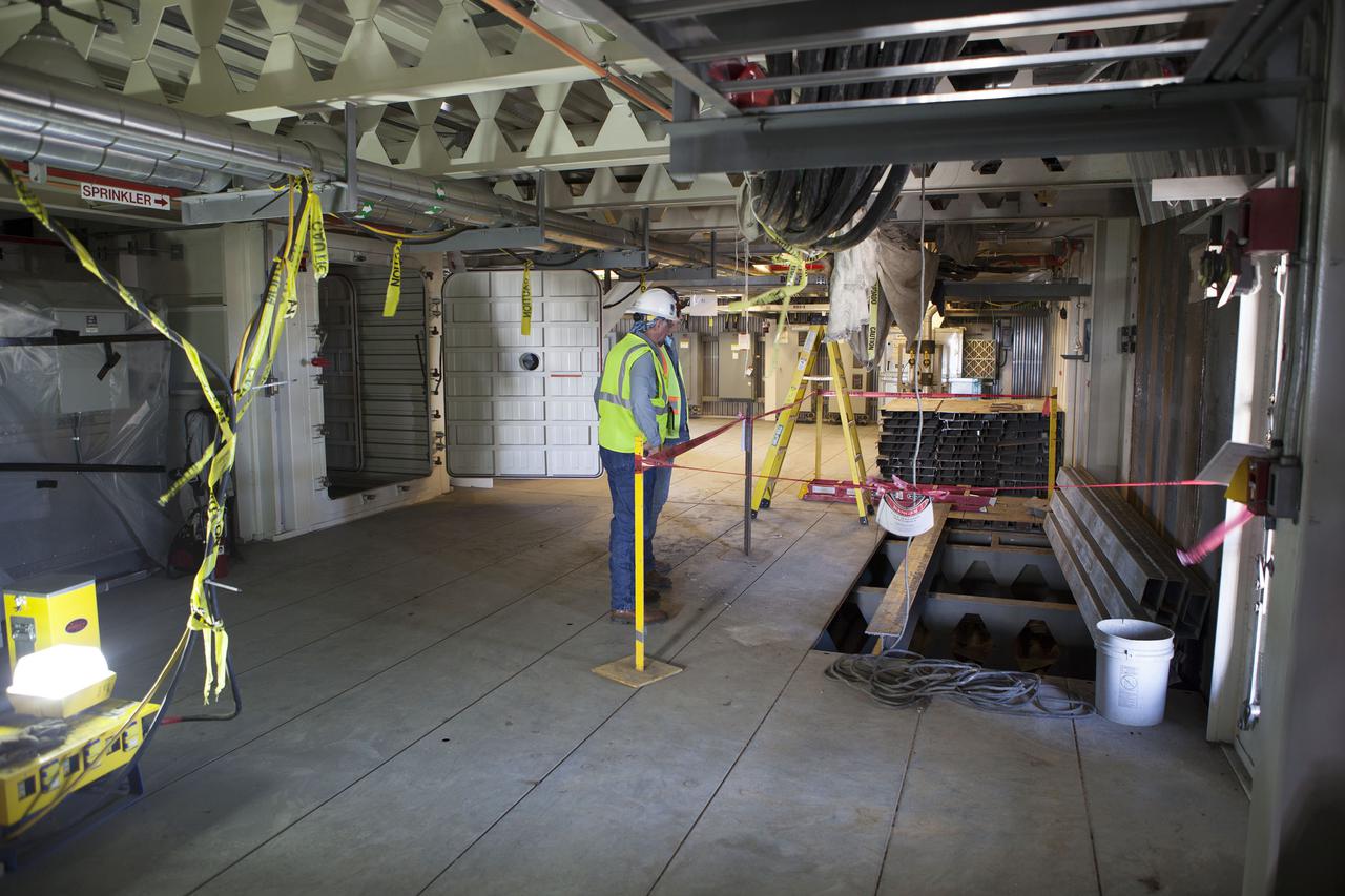 CAPE CANAVERAL, Fla. – Modifications continue on the Mobile Launcher, or ML, at the Mobile Launcher Park Site at NASA’s Kennedy Space Center in Florida. Construction workers check a roped off area beneath the surface of the ML.  In 2013, the agency awarded a contract to J.P. Donovan Construction Inc. of Rockledge, Fla., to modify the ML, which is one of the key elements of ground support equipment that is being upgraded by the Ground Systems Development and Operations Program office at Kennedy. The ML will carry the SLS rocket and Orion spacecraft to Launch Pad 39B for its first mission, Exploration Mission 1, in 2017. Photo credit: NASA_Dimitri Gerondidakis