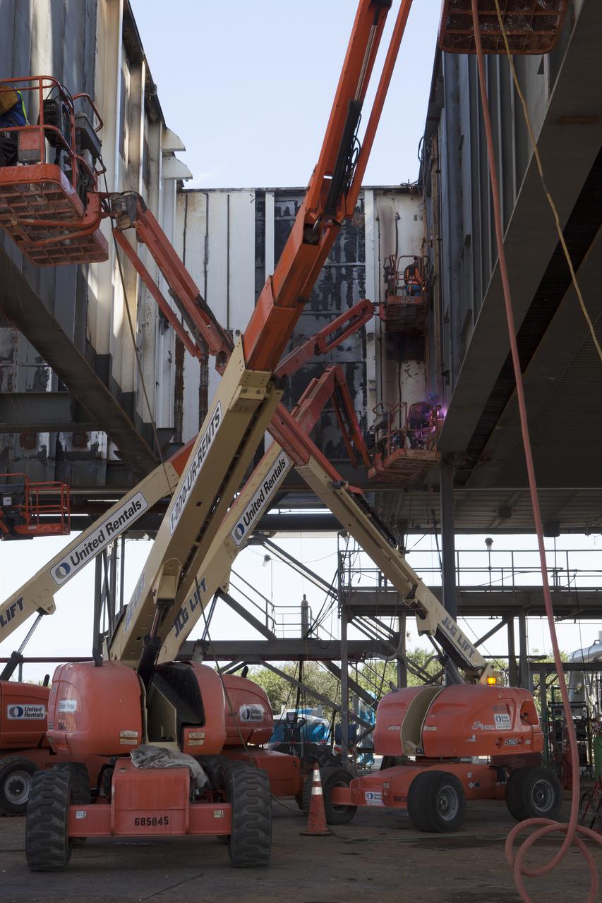 CAPE CANAVERAL, Fla. – Modifications continue on the Mobile Launcher, or ML, at the Mobile Launcher Park Site at NASA’s Kennedy Space Center in Florida. Construction workers on lifts perform welding work on the exterior of the ML.   In 2013, the agency awarded a contract to J.P. Donovan Construction Inc. of Rockledge, Fla., to modify the ML, which is one of the key elements of ground support equipment that is being upgraded by the Ground Systems Development and Operations Program office at Kennedy. The ML will carry the SLS rocket and Orion spacecraft to Launch Pad 39B for its first mission, Exploration Mission 1, in 2017. Photo credit: NASA_Dimitri Gerondidakis