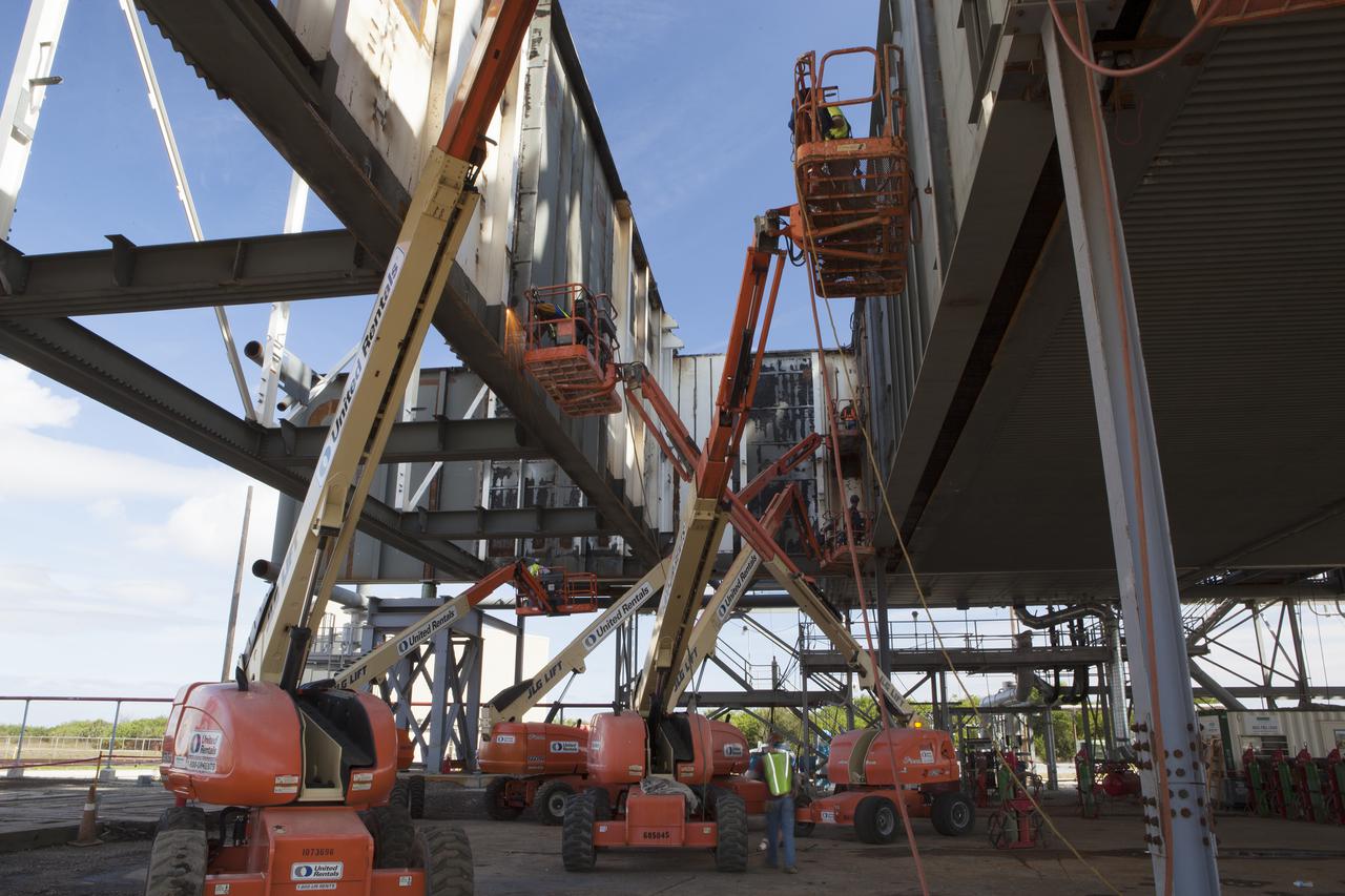 CAPE CANAVERAL, Fla. – Modifications continue on the Mobile Launcher, or ML, at the Mobile Launcher Park Site at NASA’s Kennedy Space Center in Florida. Construction workers on lifts perform welding work on the exterior of the ML.   In 2013, the agency awarded a contract to J.P. Donovan Construction Inc. of Rockledge, Fla., to modify the ML, which is one of the key elements of ground support equipment that is being upgraded by the Ground Systems Development and Operations Program office at Kennedy. The ML will carry the SLS rocket and Orion spacecraft to Launch Pad 39B for its first mission, Exploration Mission 1, in 2017. Photo credit: NASA_Dimitri Gerondidakis