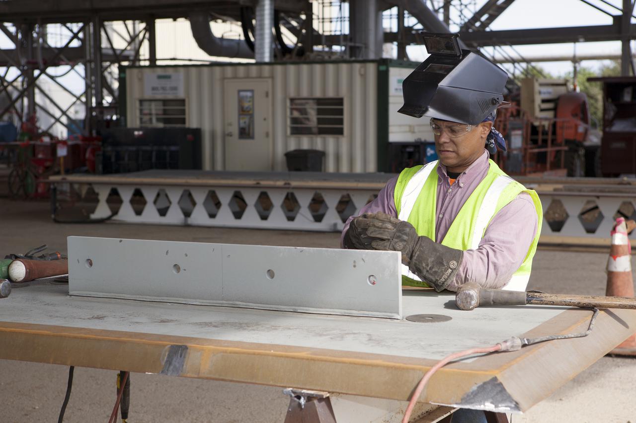 CAPE CANAVERAL, Fla. – Modifications continue on the Mobile Launcher, or ML, at the Mobile Launcher Park Site at NASA’s Kennedy Space Center in Florida. A construction worker prepares a metal part for installation on the ML.  In 2013, the agency awarded a contract to J.P. Donovan Construction Inc. of Rockledge, Fla., to modify the ML, which is one of the key elements of ground support equipment that is being upgraded by the Ground Systems Development and Operations Program office at Kennedy. The ML will carry the SLS rocket and Orion spacecraft to Launch Pad 39B for its first mission, Exploration Mission 1, in 2017. Photo credit: NASA_Dimitri Gerondidakis