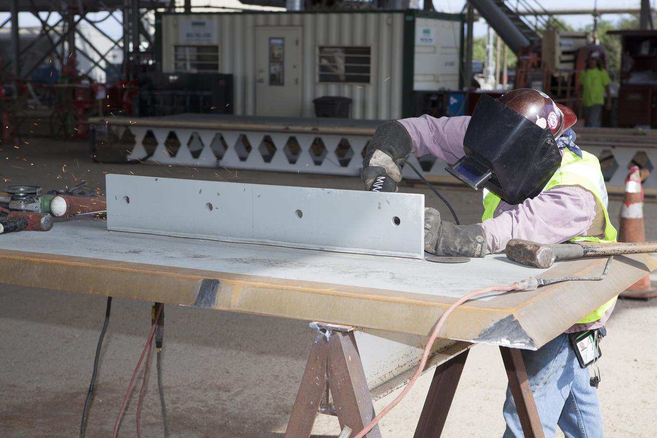 CAPE CANAVERAL, Fla. – Modifications continue on the Mobile Launcher, or ML, at the Mobile Launcher Park Site at NASA’s Kennedy Space Center in Florida. A construction worker prepares a metal part for installation on the ML.  In 2013, the agency awarded a contract to J.P. Donovan Construction Inc. of Rockledge, Fla., to modify the ML, which is one of the key elements of ground support equipment that is being upgraded by the Ground Systems Development and Operations Program office at Kennedy. The ML will carry the SLS rocket and Orion spacecraft to Launch Pad 39B for its first mission, Exploration Mission 1, in 2017. Photo credit: NASA_Dimitri Gerondidakis