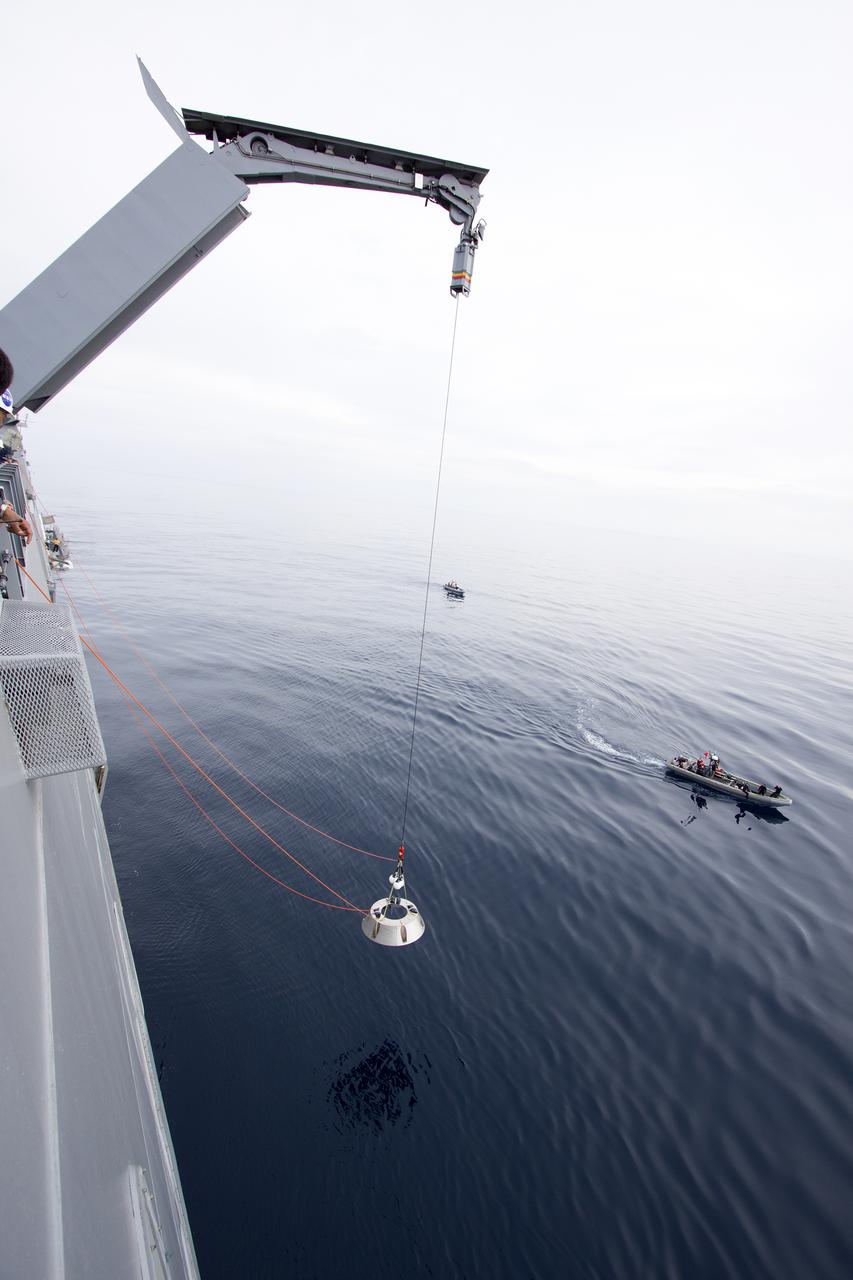 SAN DIEGO, Calif. – On the USS San Diego, a crane is used to lower the forward bay cover, attached to tether lines, into the Pacific Ocean as part of the Orion underway recovery test. The Orion boilerplate test vehicle and other hardware are secured in the well deck of the ship in preparation for the test about 100 miles off the coast of San Diego, California. NASA and the U.S. Navy conducted tests to prepare for the recovery of the Orion crew module, forward bay cover and parachutes on its return from a deep space mission. The underway recovery test will allow the teams to demonstrate and evaluate the recovery processes, procedures, hardware and personnel in open waters. During the testing, the tether lines were unable to support the tension caused by crew module motion that was driven by wave turbulence in the well deck of the ship. NASA and the U.S. Navy are reviewing the testing data collected to evaluate the next steps. The Ground Systems Development and Operations Program conducted the underway recovery tests. Orion is the exploration spacecraft designed to carry astronauts to destinations not yet explored by humans, including an asteroid and Mars. It will have emergency abort capability, sustain the crew during space travel and provide safe re-entry from deep space return velocities. The first unpiloted test flight of the Orion is scheduled to launch in 2014 atop a Delta IV rocket and in 2017 on NASA’s Space Launch System rocket. For more information, visit http:__www.nasa.gov_orion. Photo credit: NASA_Cory Huston