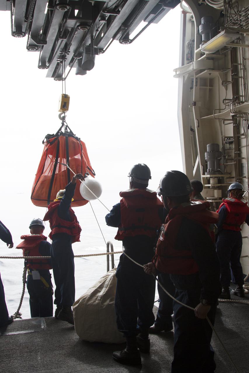 SAN DIEGO, Calif. – On the USS San Diego, NASA and U.S. Navy personnel use a crane to lower a parachute into a rigid hull inflatable boat as part of the Orion underway recovery test. The Orion boilerplate test vehicle and other hardware are secured in the well deck of the ship in preparation for the test about 100 miles off the coast of San Diego, California. NASA and the U.S. Navy conducted tests to prepare for the recovery of the Orion crew module, forward bay cover and parachutes on its return from a deep space mission. The underway recovery test will allow the teams to demonstrate and evaluate the recovery processes, procedures, hardware and personnel in open waters. During the testing, the tether lines were unable to support the tension caused by crew module motion that was driven by wave turbulence in the well deck of the ship. NASA and the U.S. Navy are reviewing the testing data collected to evaluate the next steps. The Ground Systems Development and Operations Program conducted the underway recovery tests. Orion is the exploration spacecraft designed to carry astronauts to destinations not yet explored by humans, including an asteroid and Mars. It will have emergency abort capability, sustain the crew during space travel and provide safe re-entry from deep space return velocities. The first unpiloted test flight of the Orion is scheduled to launch in 2014 atop a Delta IV rocket and in 2017 on NASA’s Space Launch System rocket. For more information, visit http:__www.nasa.gov_orion. Photo credit: NASA_Cory Huston