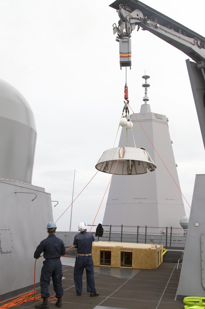 SAN DIEGO, Calif. – On a deck of the USS San Diego, U.S. Navy personnel use a crane and tether lines to lower the Orion forward bay cover into the water as part of the Orion underway recovery test. The Orion boilerplate test vehicle and other hardware are secured in the well deck of the ship in preparation for the test about 100 miles off the coast of San Diego, California. NASA and the U.S. Navy conducted tests to prepare for the recovery of the Orion crew module, forward bay cover and parachutes on its return from a deep space mission. The underway recovery test will allow the teams to demonstrate and evaluate the recovery processes, procedures, hardware and personnel in open waters. During the testing, the tether lines were unable to support the tension caused by crew module motion that was driven by wave turbulence in the well deck of the ship. NASA and the U.S. Navy are reviewing the testing data collected to evaluate the next steps. The Ground Systems Development and Operations Program conducted the underway recovery tests. Orion is the exploration spacecraft designed to carry astronauts to destinations not yet explored by humans, including an asteroid and Mars. It will have emergency abort capability, sustain the crew during space travel and provide safe re-entry from deep space return velocities. The first unpiloted test flight of the Orion is scheduled to launch in 2014 atop a Delta IV rocket and in 2017 on NASA’s Space Launch System rocket. For more information, visit http:__www.nasa.gov_orion. Photo credit: NASA_Cory Huston