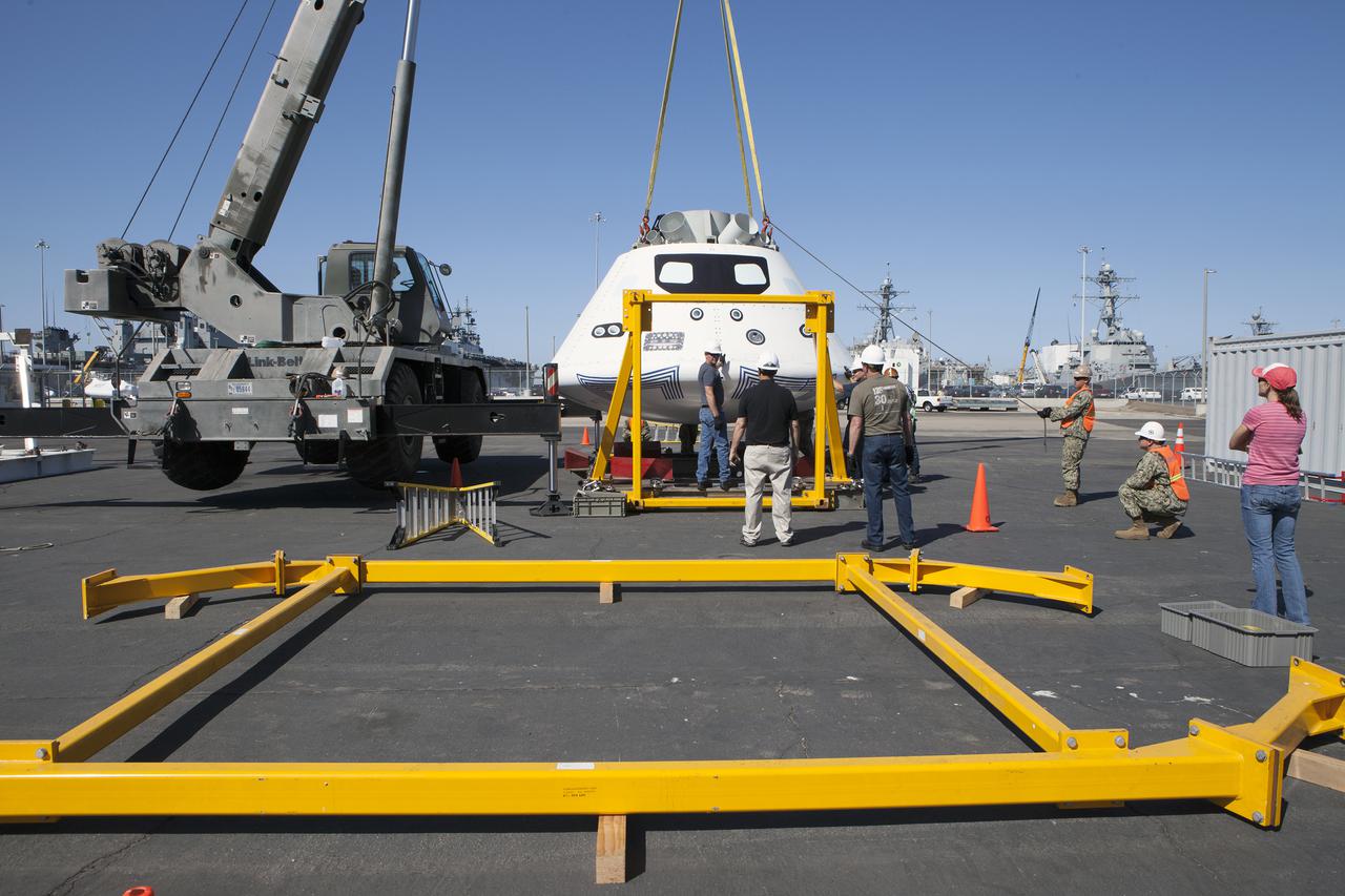 SAN DIEGO, Calif. – A crane lowers the Orion boilerplate test vehicle onto the crew module recovery cradle at a warehouse at the Naval Base San Diego in California. The Ground Systems Development and Operations Program, Lockheed Martin and the U.S. Navy are evaluating the hardware and processes for preparing the Orion crew module for Exploration Flight Test-1, or EFT-1, for overland transport from the naval base to NASA's Kennedy Space Center in Florida.  Orion is the exploration spacecraft designed to carry astronauts to destinations not yet explored by humans, including an asteroid and Mars. It will have emergency abort capability, sustain the crew during space travel and provide safe re-entry from deep space return velocities. The first unpiloted test flight of the Orion is scheduled to launch later this year atop a Delta IV rocket from Cape Canaveral Air Force Station in Florida to an altitude of 3,600 miles above the Earth's surface. The two-orbit, four-hour flight test will help engineers evaluate the systems critical to crew safety including the heat shield, parachute system and launch abort system. For more information, visit http:__www.nasa.gov_orion. Photo credit: NASA_Kim Shiflett