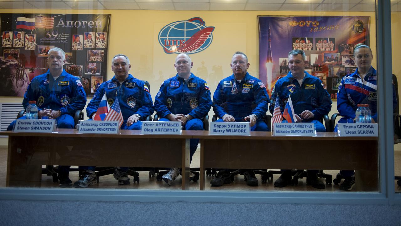 Expedition 39 primary crew flight engineer Steve Swanson of NASA, Soyuz commander Aleksander Skvortsov of the Russian Federal Space Agency, Roscosmos, flight engineer Oleg Artemyev of Roscosmos and Expedition 39 backup crew Barry Wilmore of NASA, Alexander Samokutyaev of Roscosmos, and Elena Serova of Roscosmos are seen in quarantine, behind glass, during the final press conference be Monday, March 24, 2014, at the Cosmonaut Hotel in Baikonur, Kazakhstan. The mission to the International Space Station is set to launch March 26 from the Baikonur Cosmodrome. Photo Credit: (NASA/Joel Kowsky)