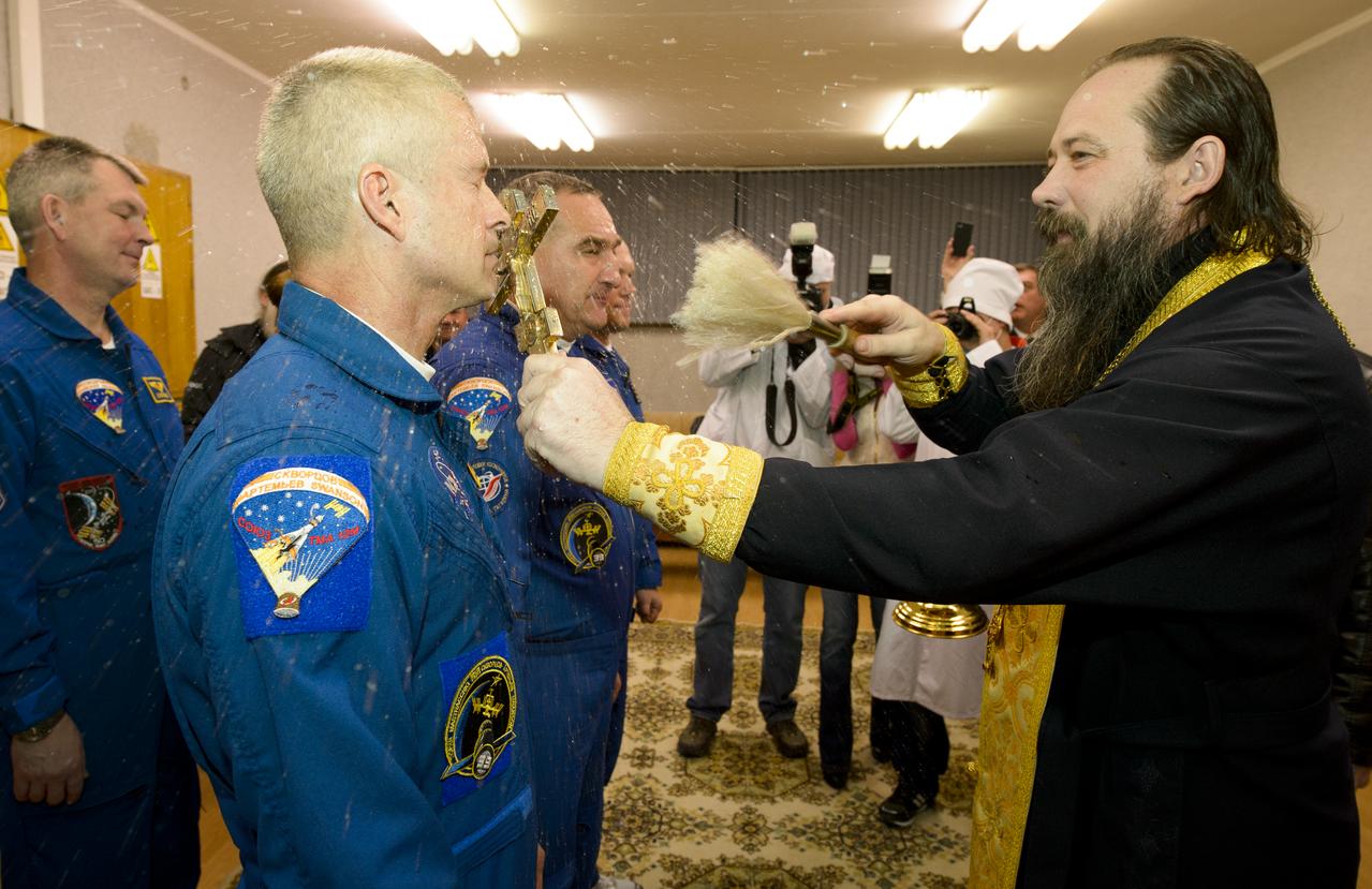 Expedition 39 Flight Engineer Steve Swanson of NASA, left, receives the traditional blessing from a Russian Orthodox priest at the Cosmonaut Hotel prior to his launch on the Soyuz rocket to the International Space Station, Tuesday, March 25, 2014, in Baikonur, Kazakhstan. Swanson, Soyuz Commander Alexander Skvortsov of the Russian Federal Space Agency, Roscosmos, and Flight Engineer Oleg Artemyev of Roscosmos will spend six months living and working aboard the ISS.  Photo Credit: (NASA/Joel Kowsky)