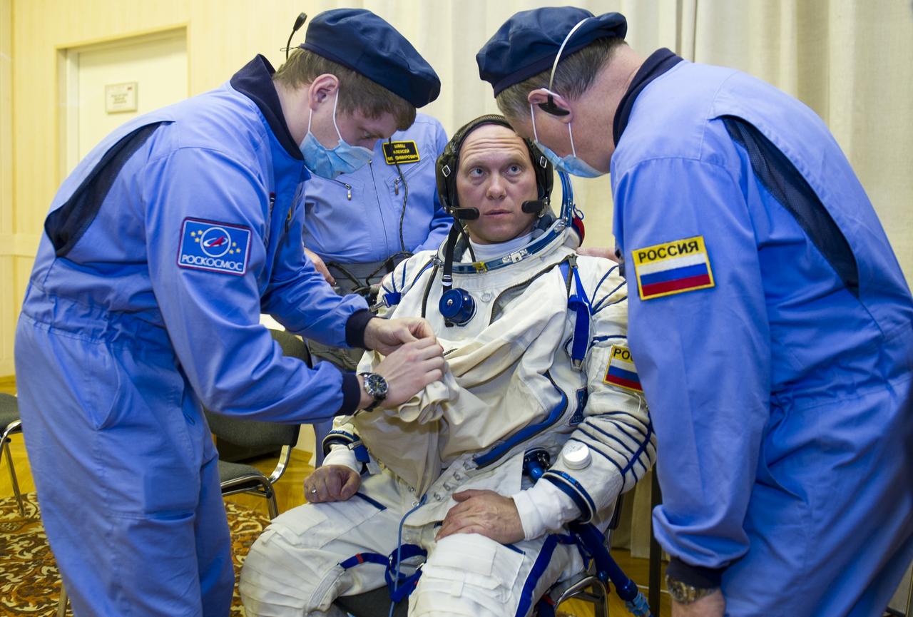 Expedition 39 Flight Engineer Oleg Artemyev of the Russian Federal Space Agency, Roscosmos, is helped into his Russian Sokol suit as he and fellow cremates, Soyuz Commander Alexander Skvortsov of Roscosmos, and Flight Engineer Steve Swanson of NASA prepare for their Soyuz launch to the International Space Station, on Tuesday, March, 25, 2014, in Baikonur, Kazakhstan. Launch of the Soyuz rocket will send Skvortsov, Swanson, and Artemyev on a six-month mission aboard the International Space Station. Photo Credit: (NASA/GCTC/Irina Peshkova)