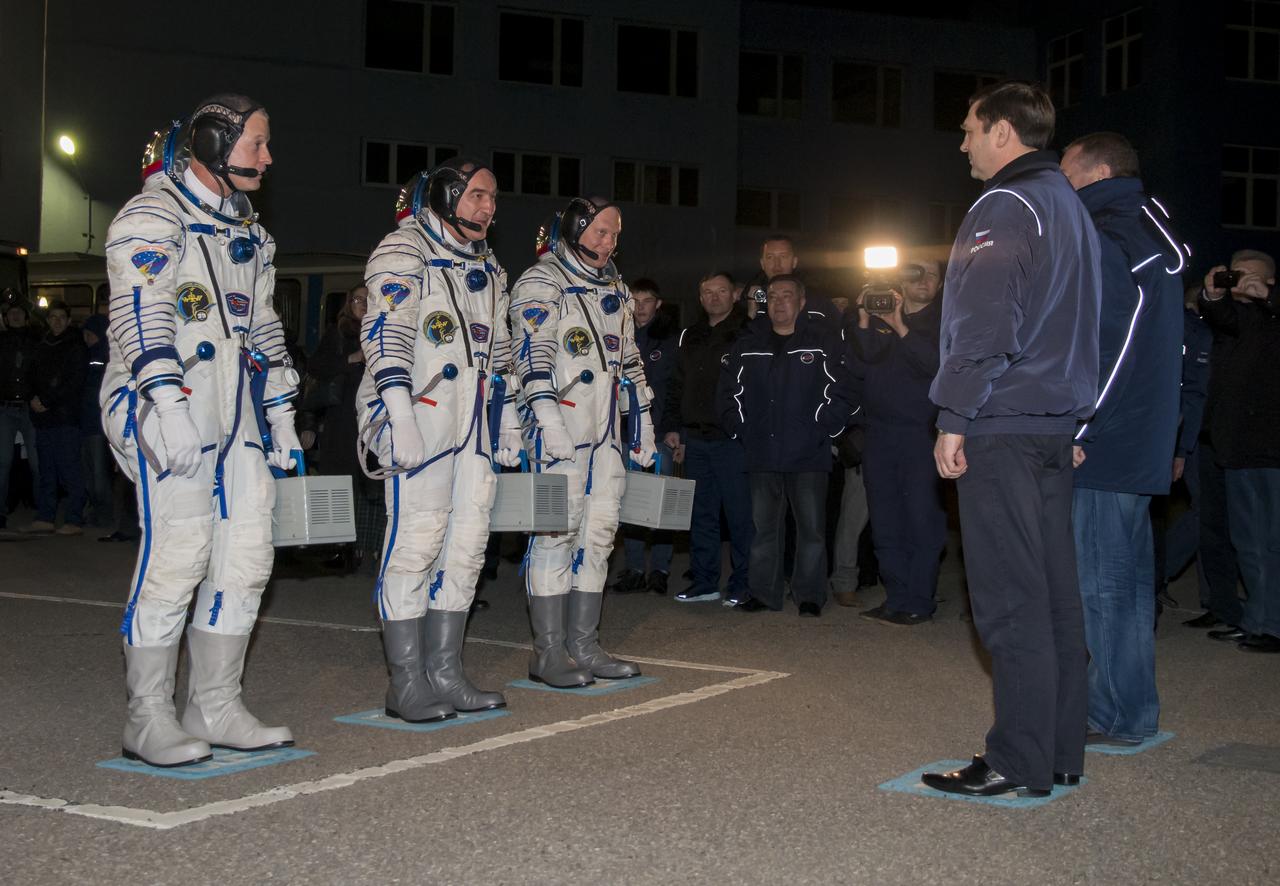 Expedition 39 Flight Engineer Steve Swanson of NASA, left, Soyuz Commander Alexander Skvortsov of the Russian Federal Space Agency, Roscosmos, center, and, Flight Engineer Oleg Artemyev of Roscosmos, right, are seen as they report to the General Director of the Russian Federal Space Agency, Roscosmos, Oleg Ostapenko, far right, outside of Building 254 following their suit up for launch, Wednesday, March 26, 2014 at the Baikonur Cosmodrome in Kazakhstan. The Soyuz spacecraft with Swanson, Skvortsov, and Artemyev onboard launched at 3:17 a.m. later that morning Kazakhstan time. Photo Credit: (NASA/Victor Zelentsov)