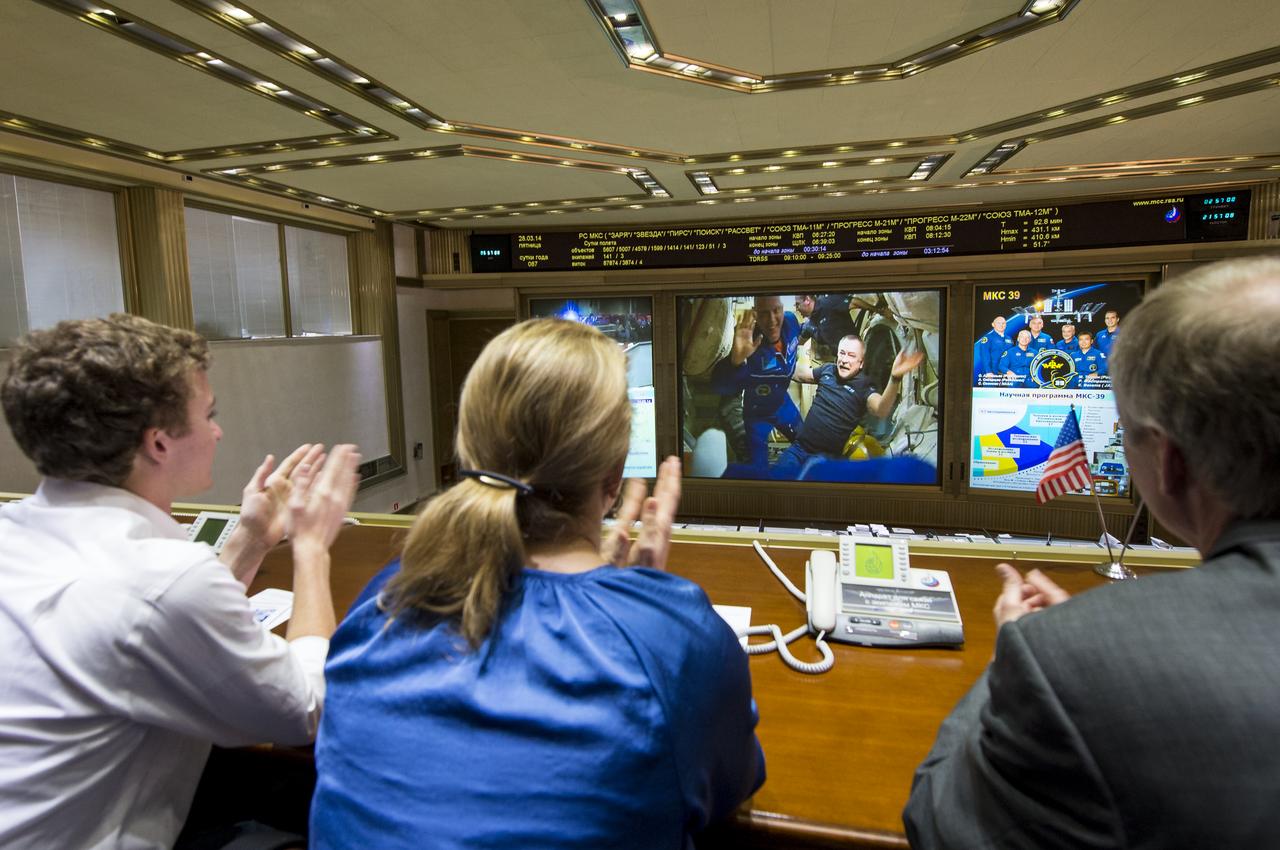 Expedition 39 Flight Engineer Oleg Artemyev of the Russian Federal Space Agency, Roscosmos, left, is seen on the TV screen at the Russian Mission Control Center in Korolev, Russia a few hours after the Soyuz TMA-12M docked to the International Space Station on Friday, March 28, 2014. Artemyev boarded the ISS with fellow crew members Soyuz Commander Alexander Skvortsov of Roscosmos, and Flight Engineer Steve Swanson of NASA. The crew of three launched at 3:17 a.m. Kazakhstan time on Wednesday, March 26 from the Baikonur Cosmodrome in Kazakhstan. Photo Credit: (NASA/Joel Kowsky)